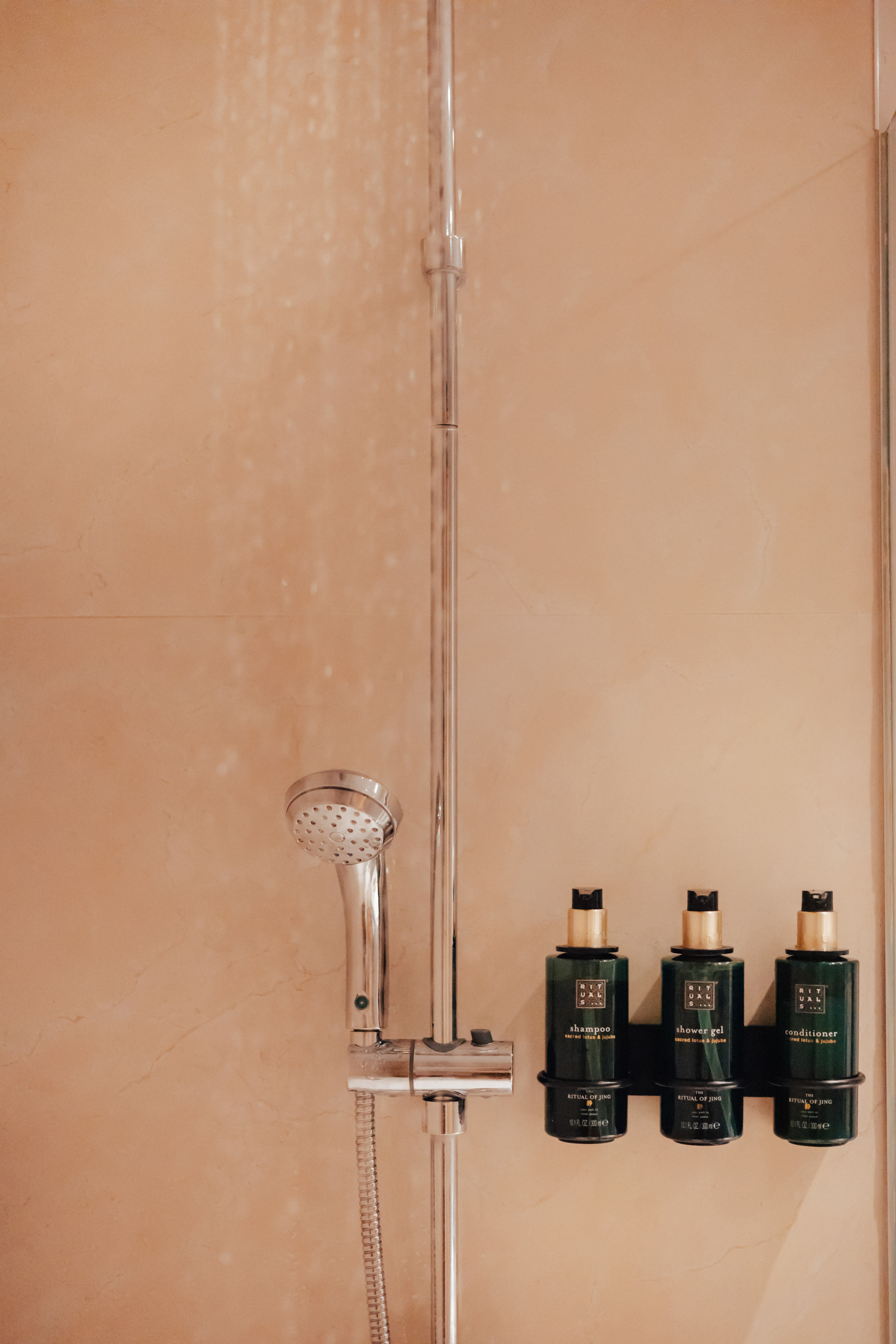 Hotel shower with Rituals of Jing shampoo, shower gel, and conditioner.