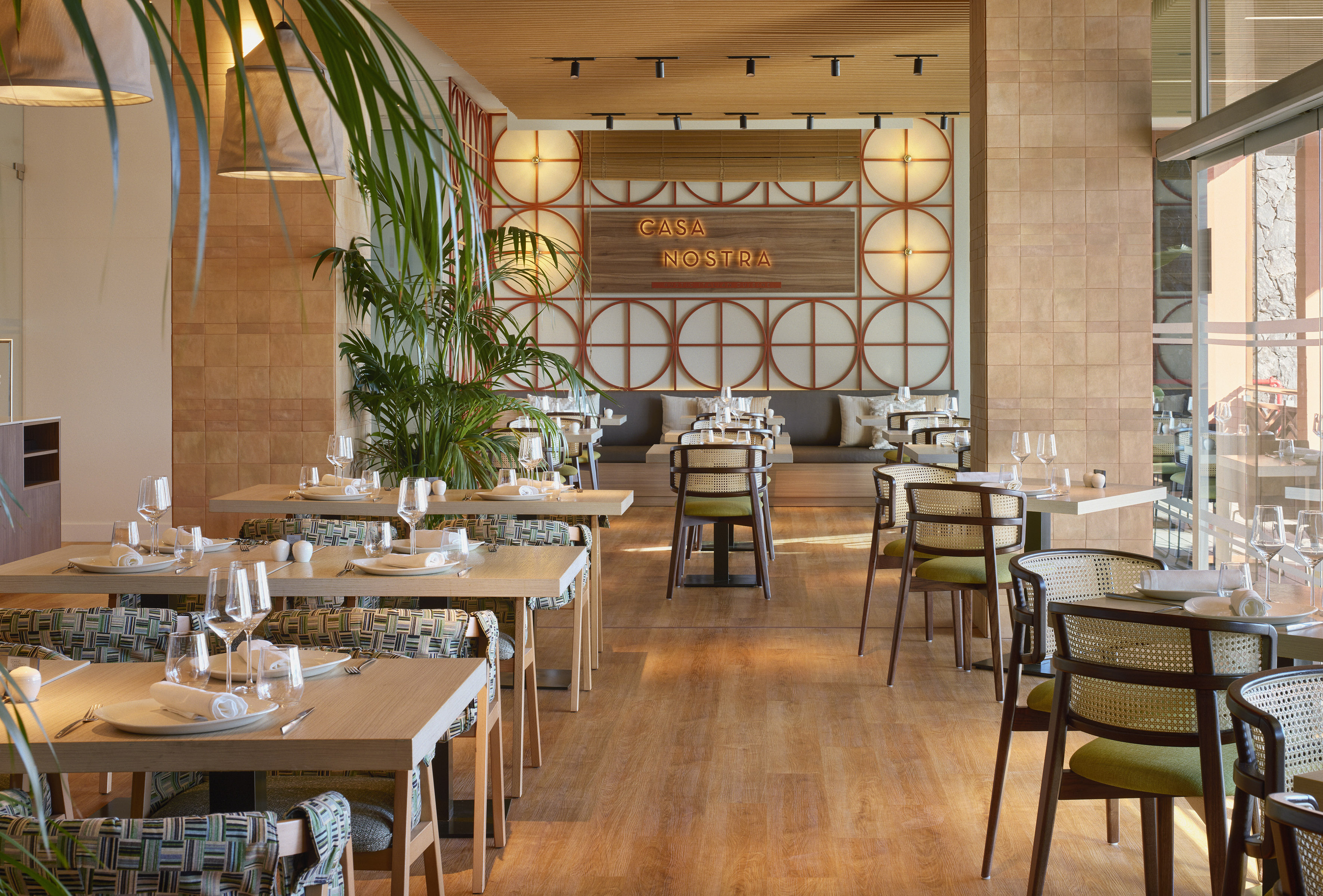 Restaurant dining room with "Casa Nostra" sign, wooden tables, and rattan chairs.