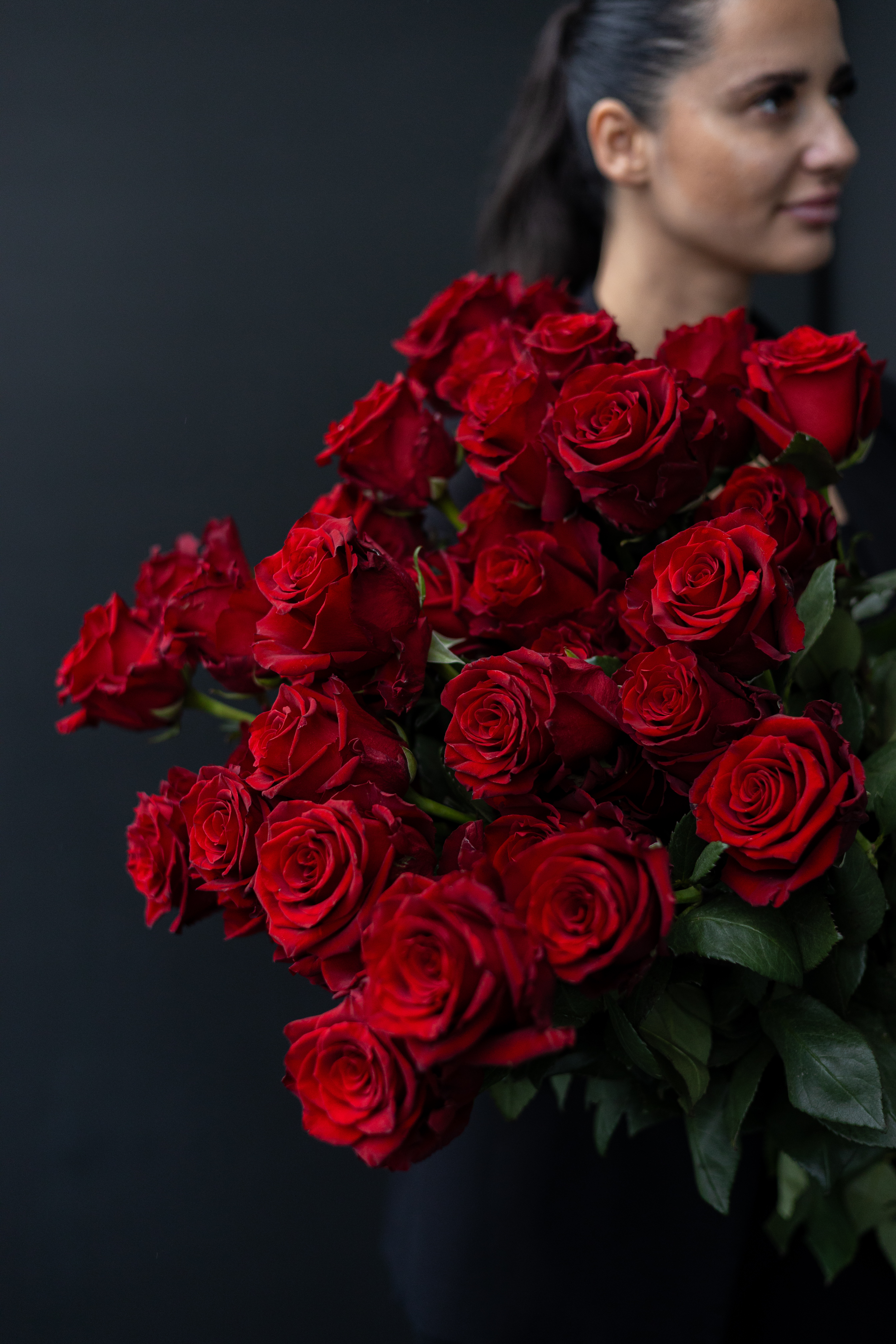 a woman holding a bouquet of red roses