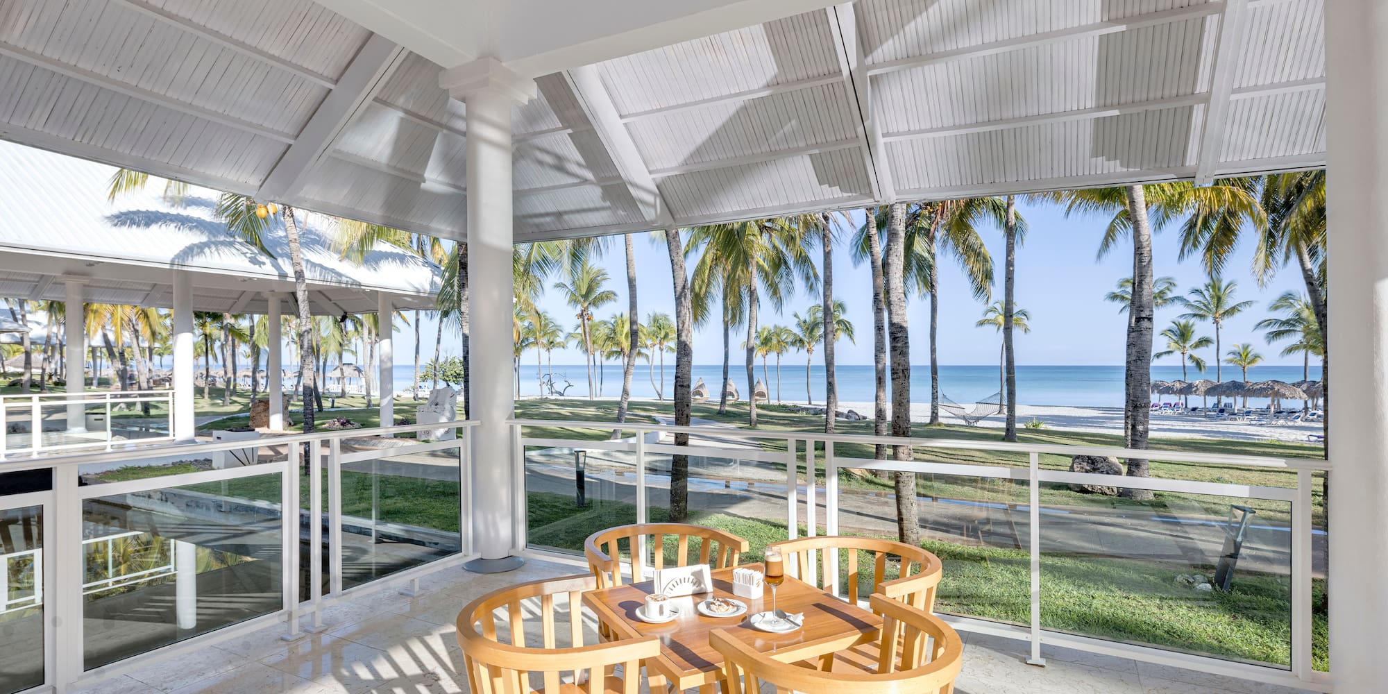 a table and chairs on a patio with a view of the ocean and trees