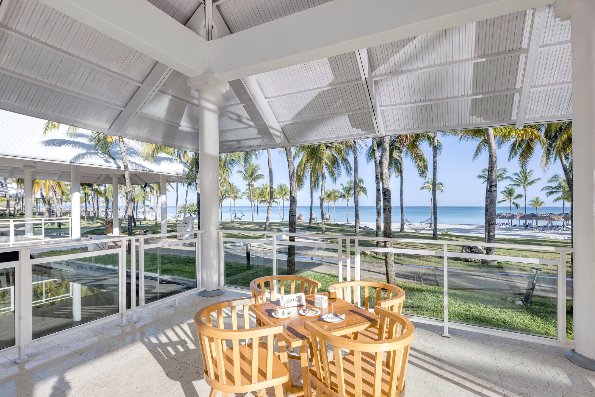 a table and chairs on a patio with a view of the ocean and trees
