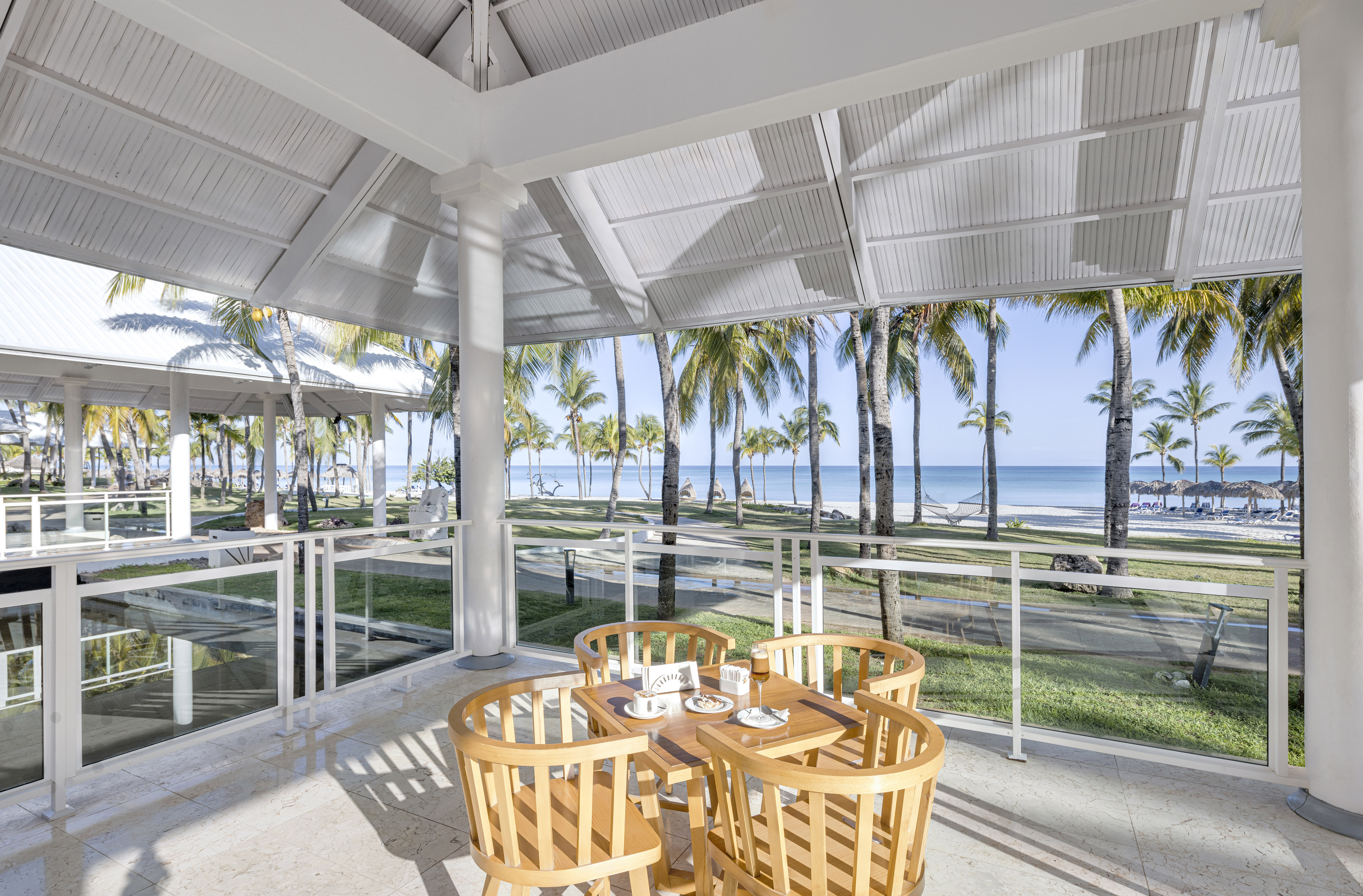 a table and chairs on a patio with a view of the ocean and trees