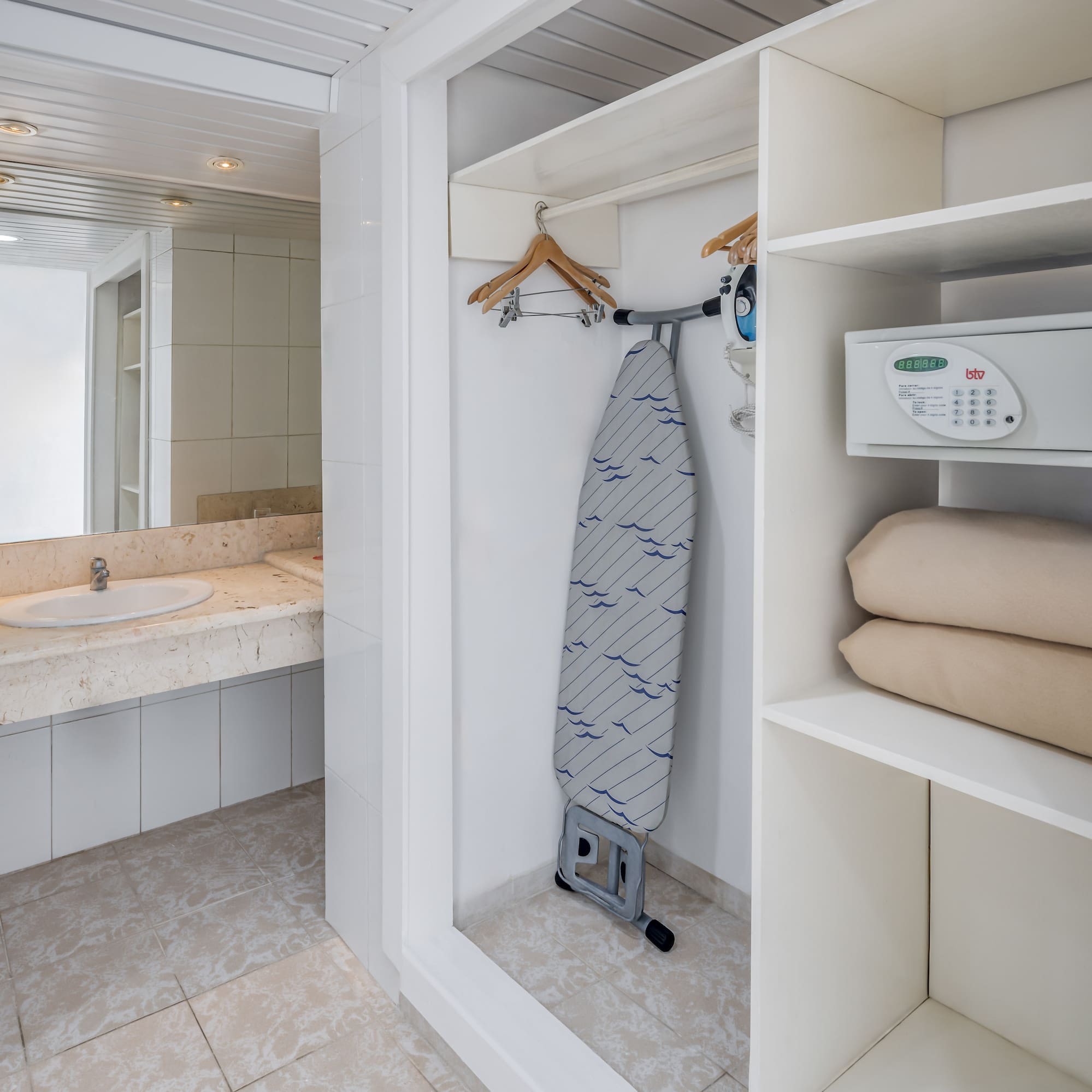 a white bathroom with a ironing board and a sink