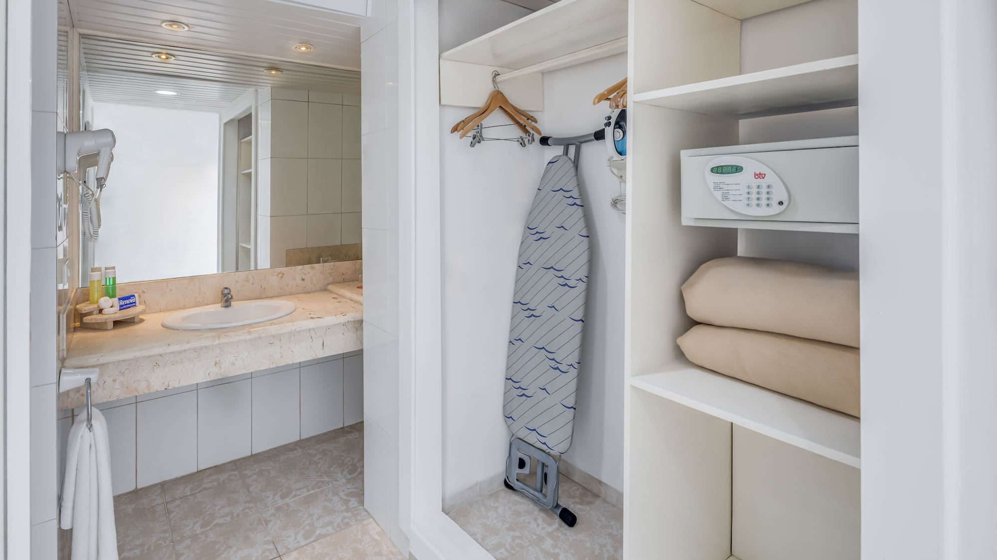 a white bathroom with a ironing board and a sink
