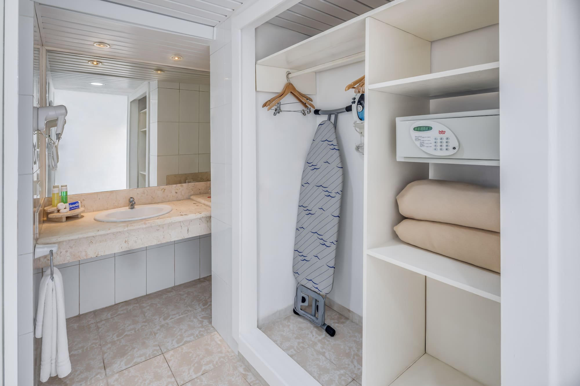 a white bathroom with a ironing board and a sink