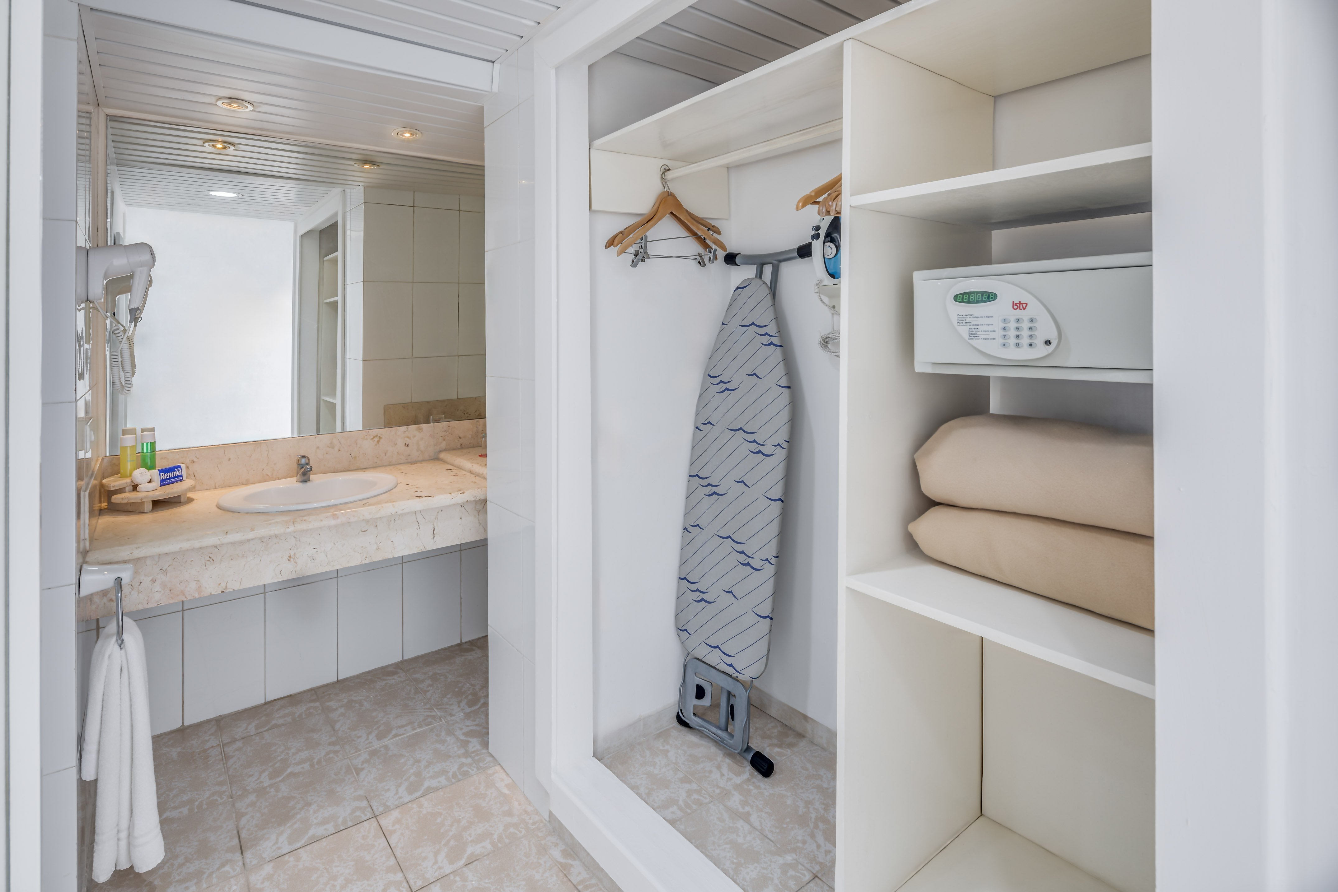 a white bathroom with a ironing board and a sink