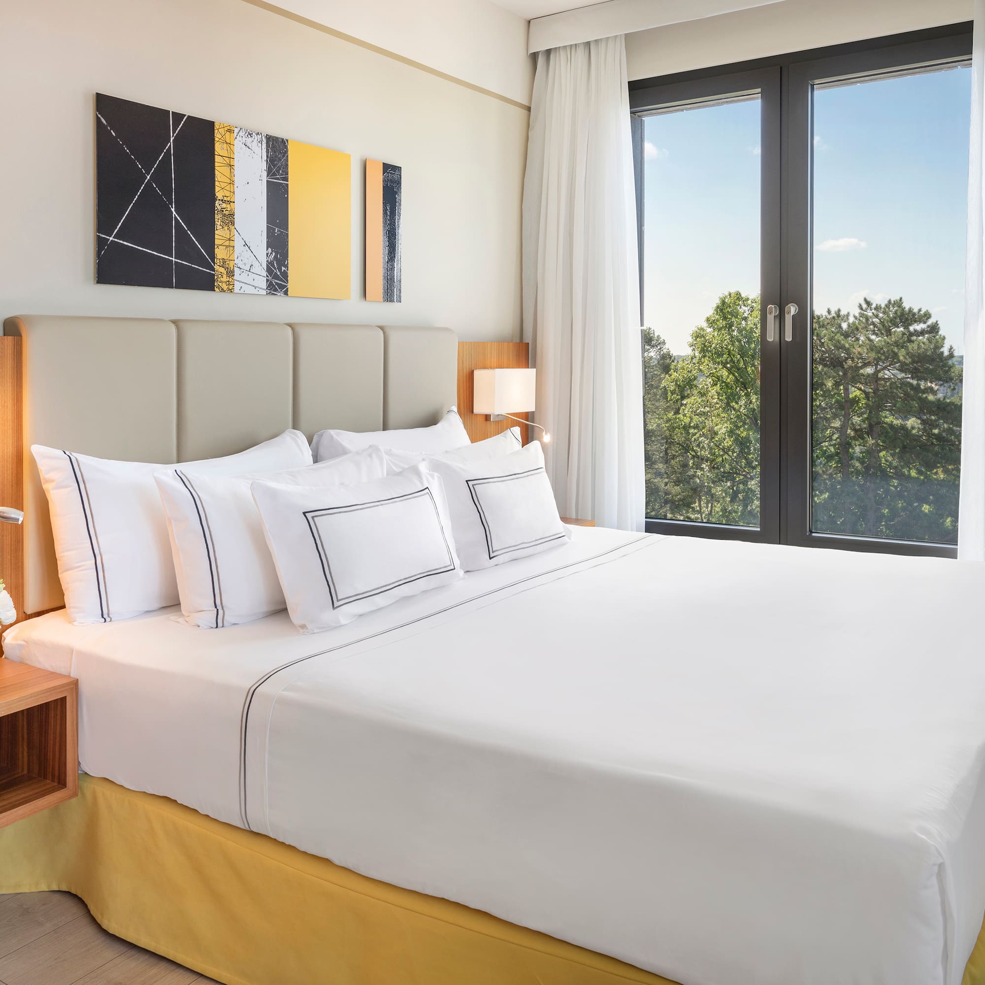 a bed with white sheets and pillows in a room with a window
