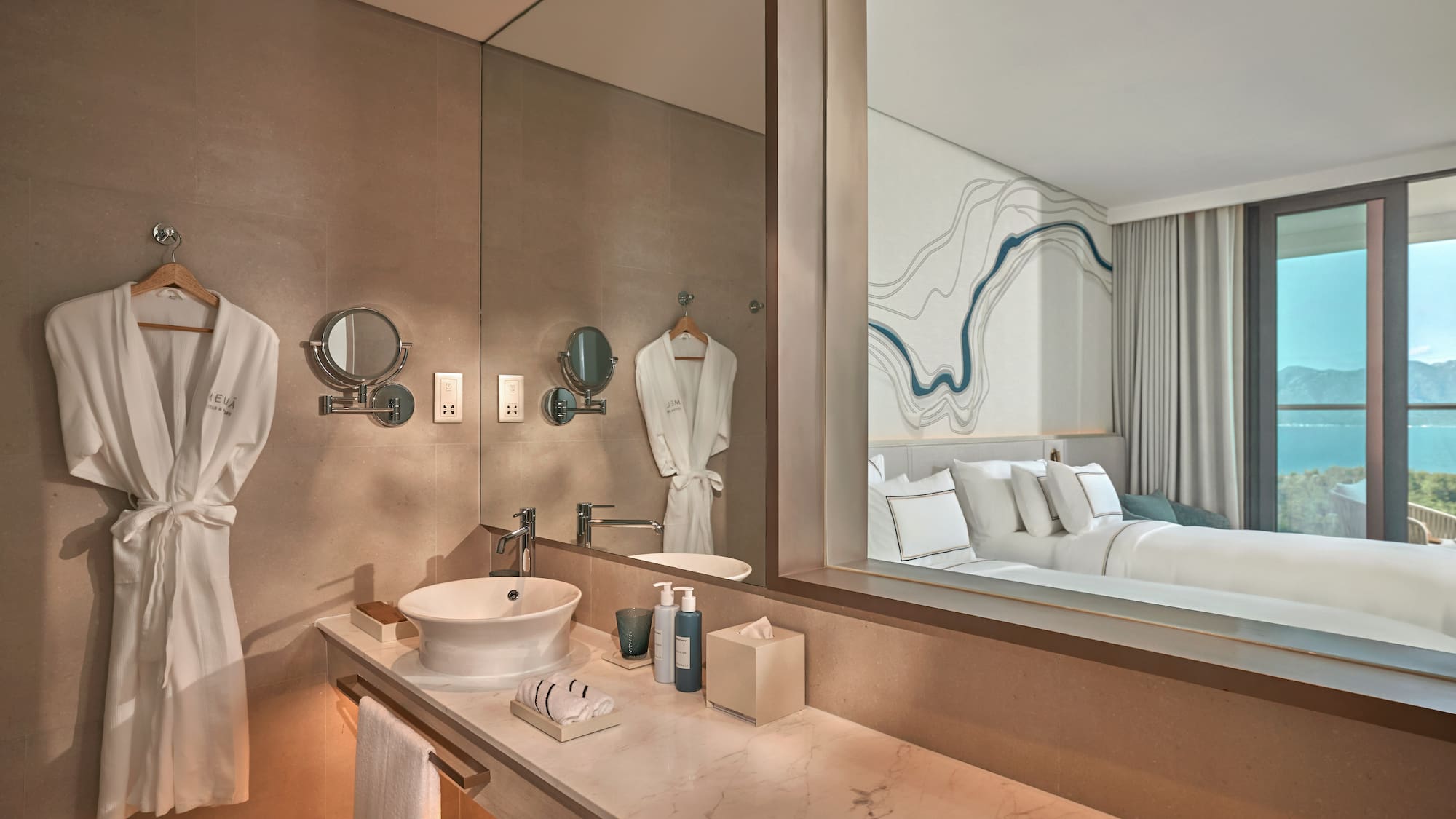 Modern hotel bathroom vanity, marble counter, mirror reflects bedroom, sea view.