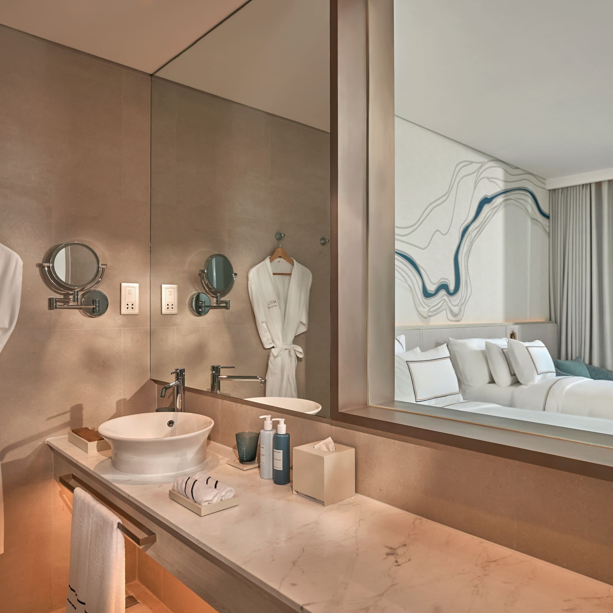 Luxury hotel bathroom vanity, reflecting modern bedroom and ocean view.