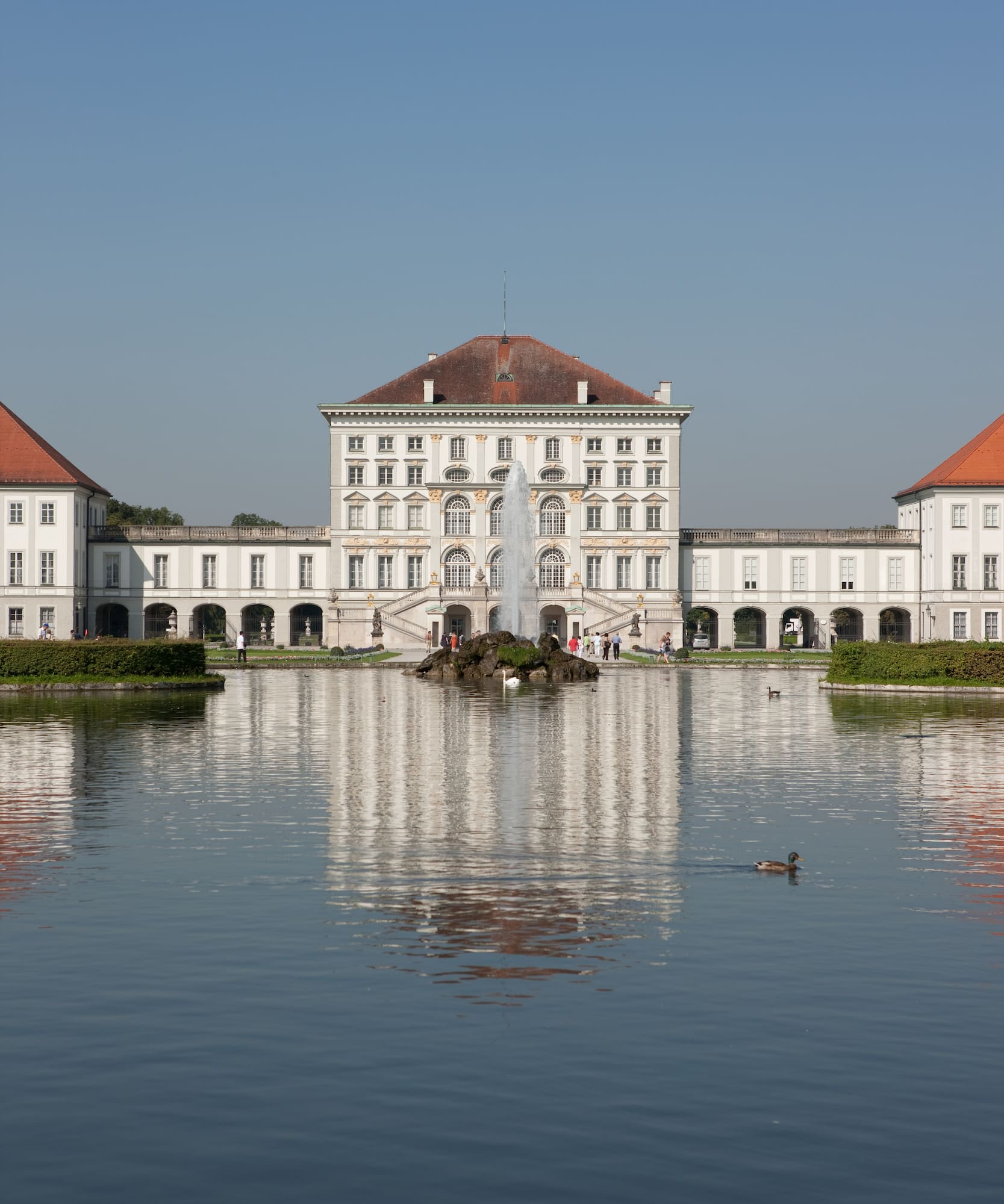 Palacio barroco Nymphenburg, Múnich, con fuente y reflejo en el estanque.