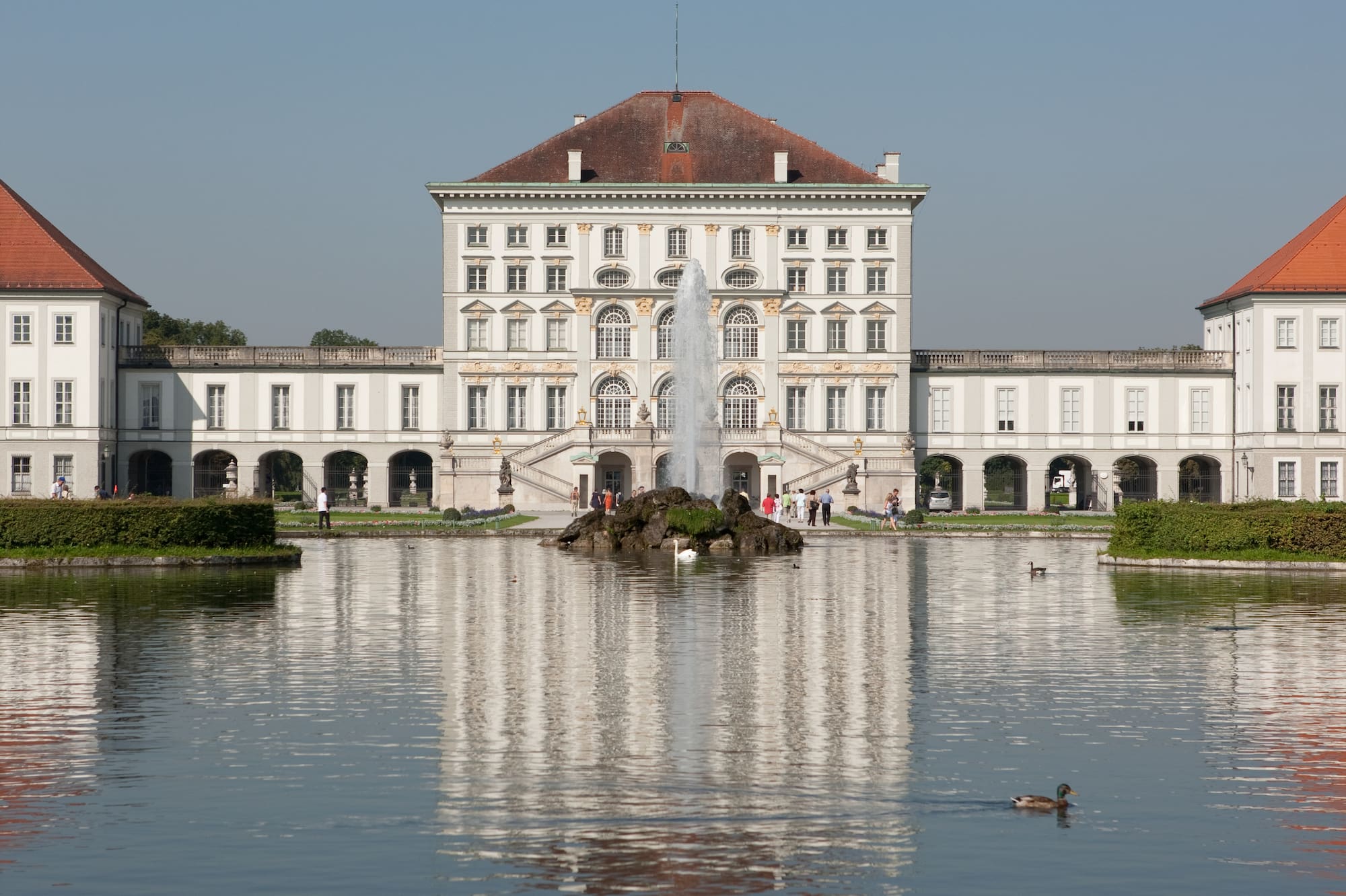 Palacio barroco Nymphenburg, Múnich, con fuente y reflejo en el estanque.