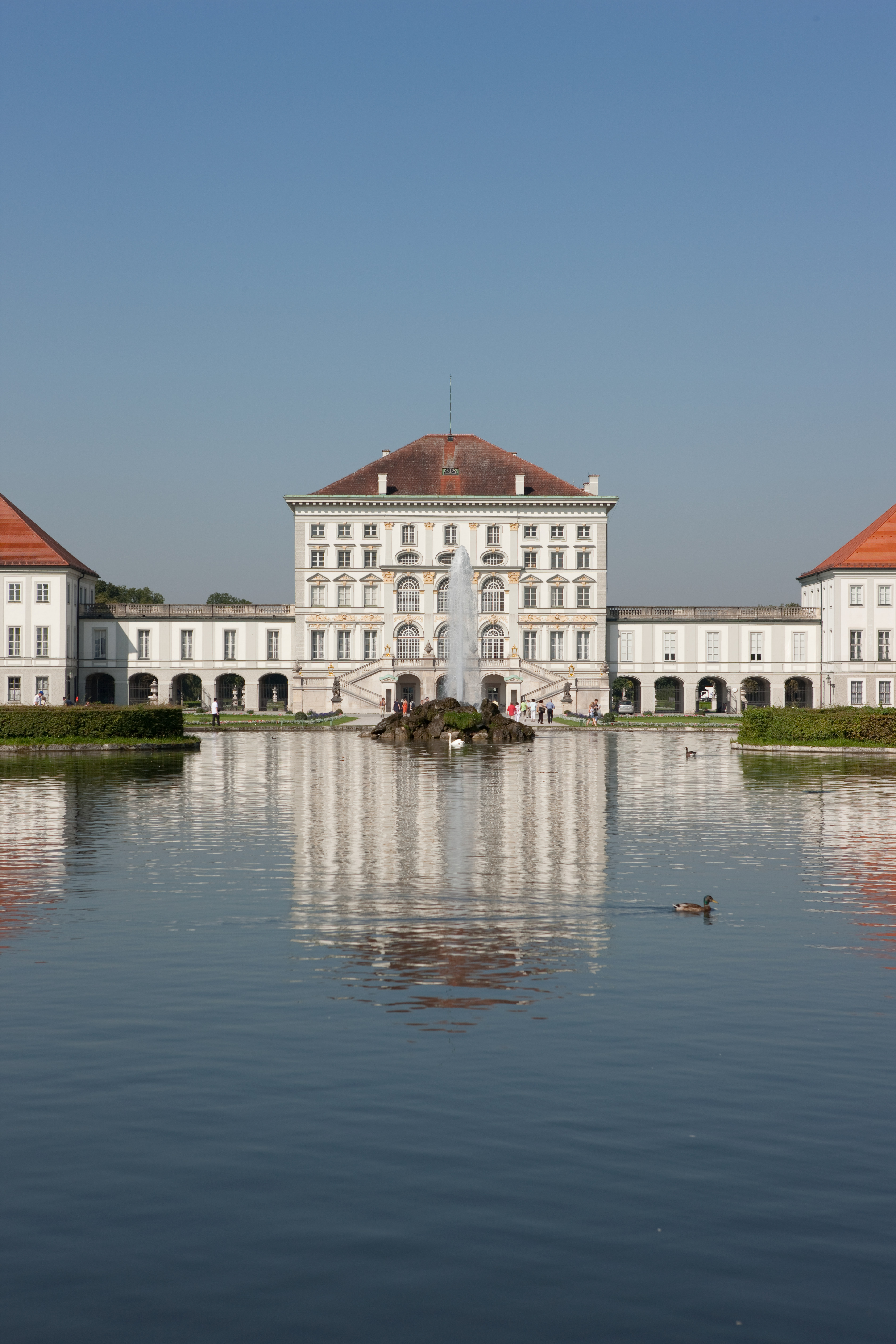 Palacio barroco Nymphenburg, Múnich, con fuente y reflejo en el estanque.