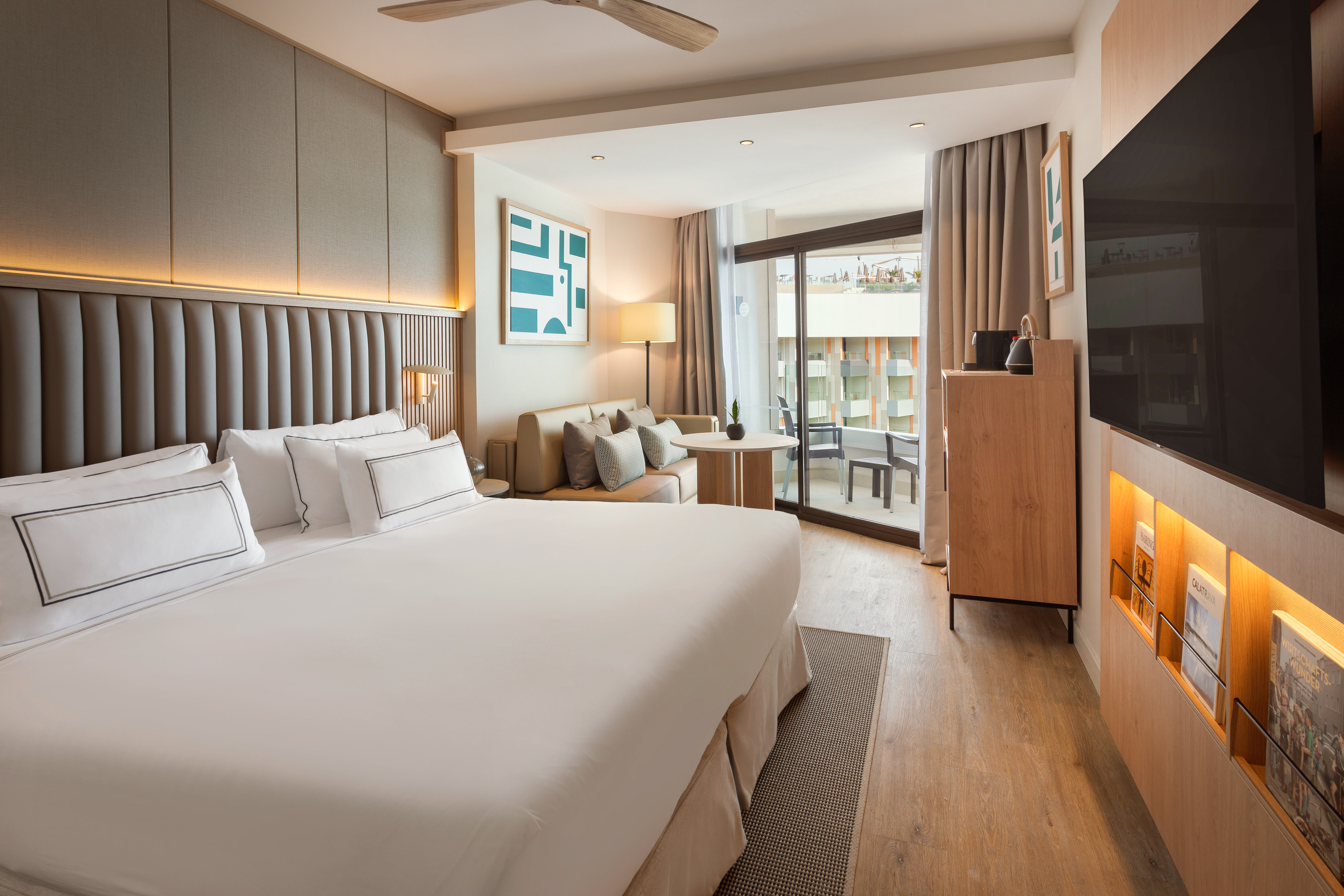 Stylish hotel room featuring king bed, seating area, and private balcony.