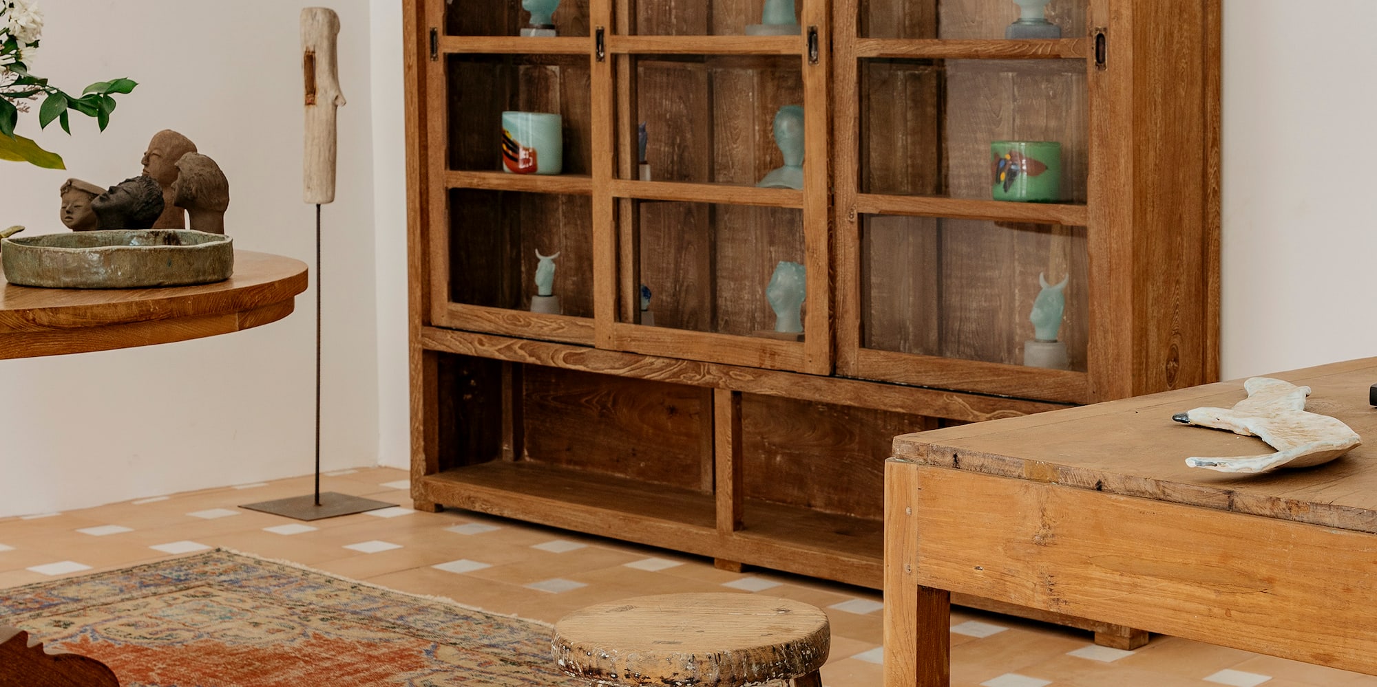 a wooden cabinet with glass doors and a stool