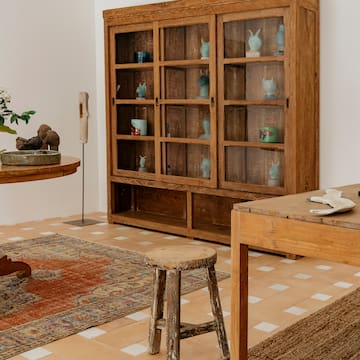 a wooden cabinet with glass doors and a stool