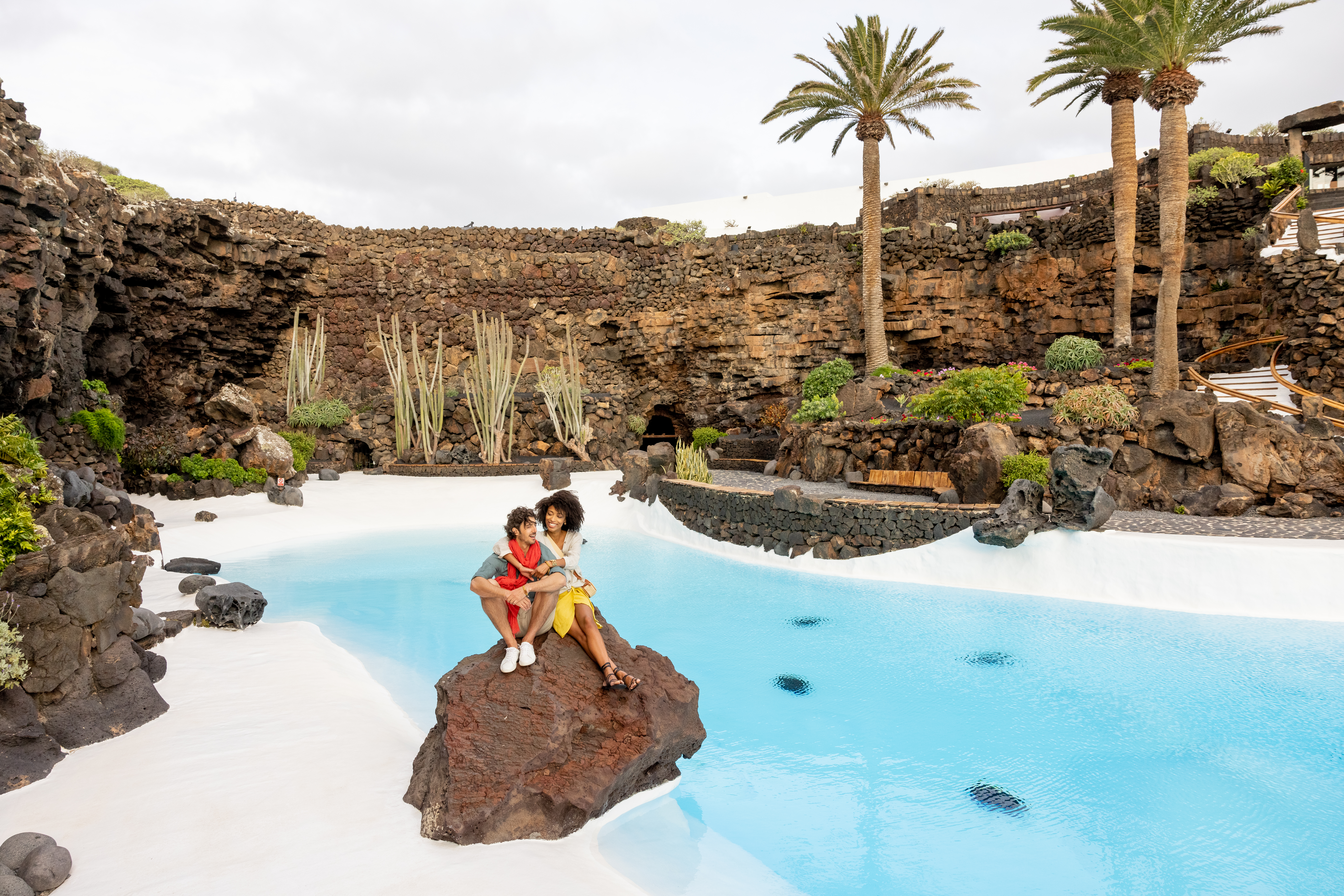 a woman and child sitting on a rock by a pool