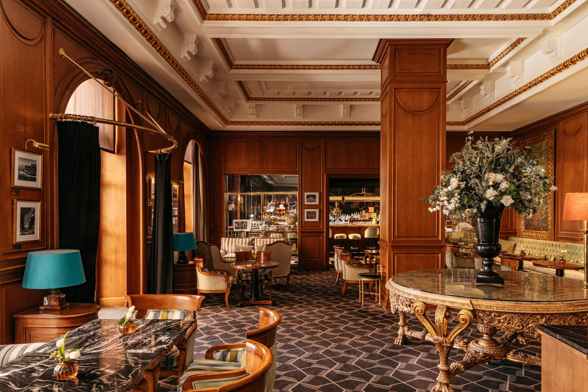 Salón de hotel de lujo con paneles de madera, bar y mobiliario elegante.