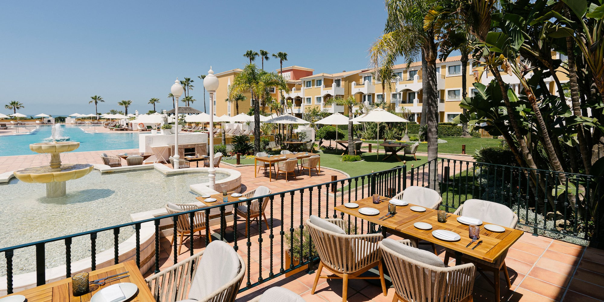 a table and chairs outside with a pool in the background