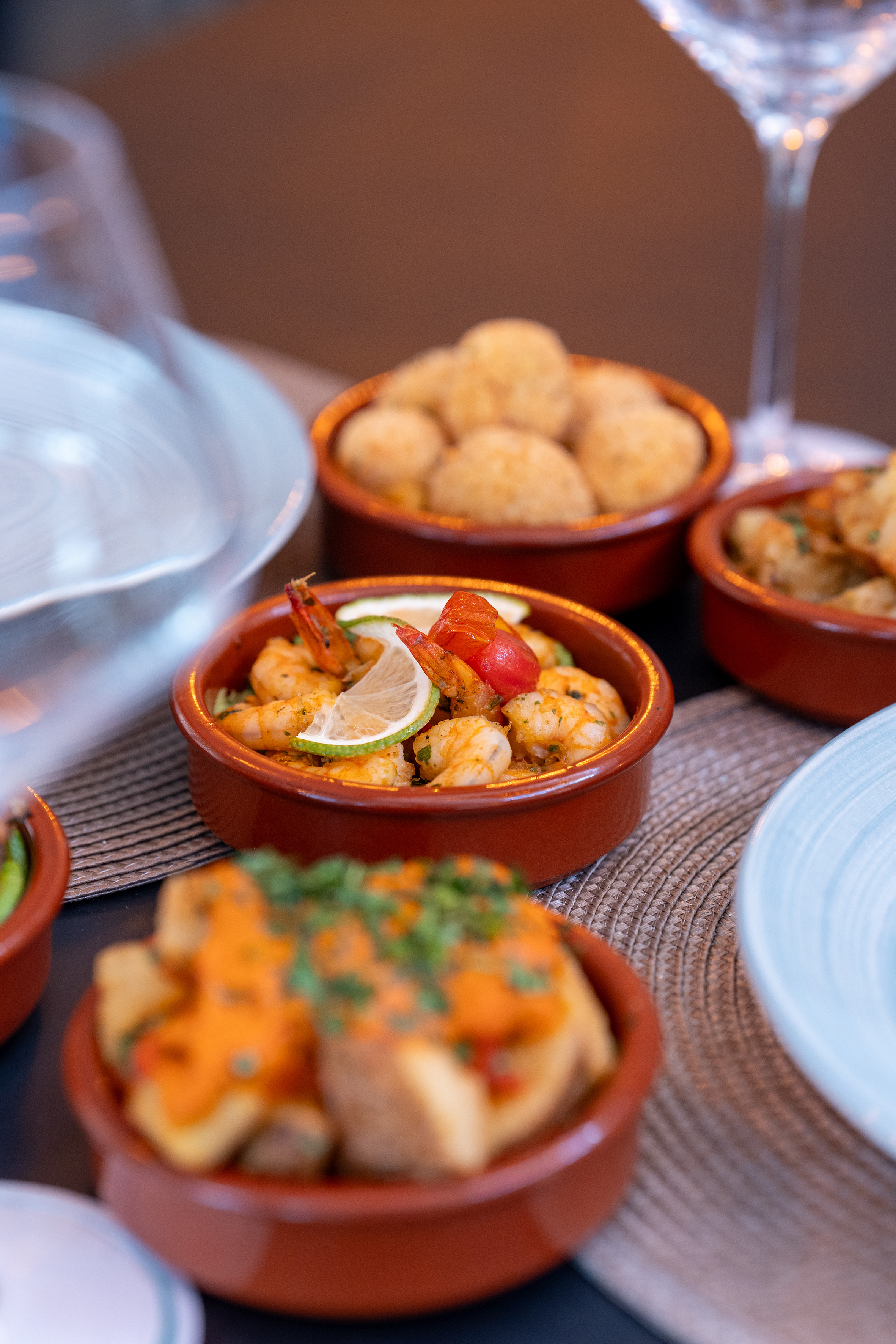 Shrimp tapas with lime, tomatoes, and various Spanish appetizers in bowls.