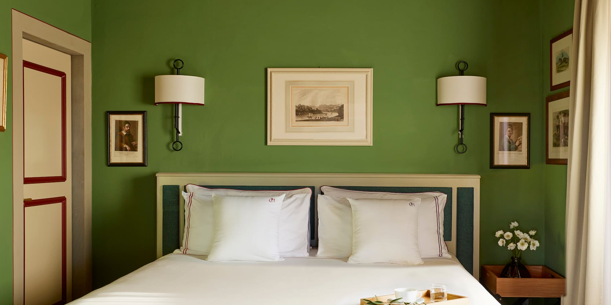 a bed with white sheets and pillows in a green room