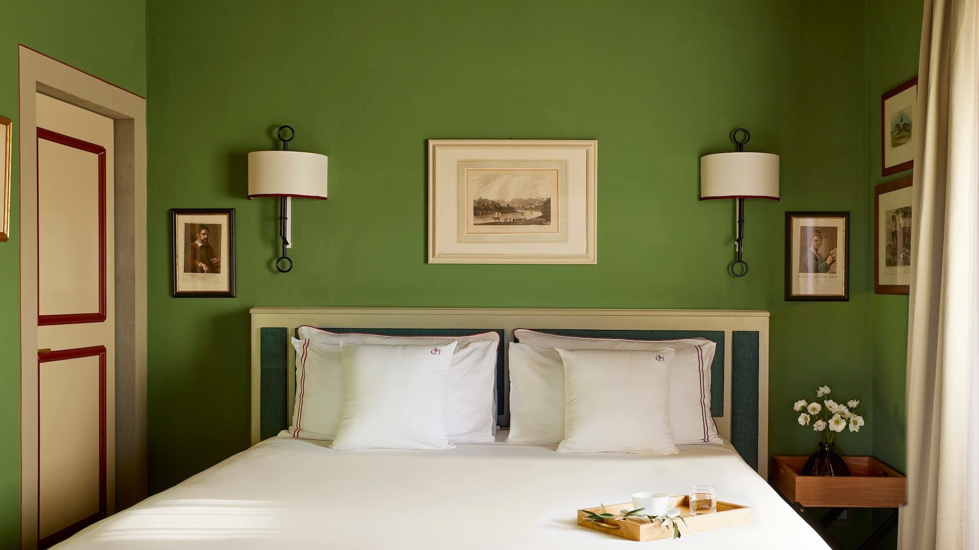 a bed with white sheets and pillows in a green room