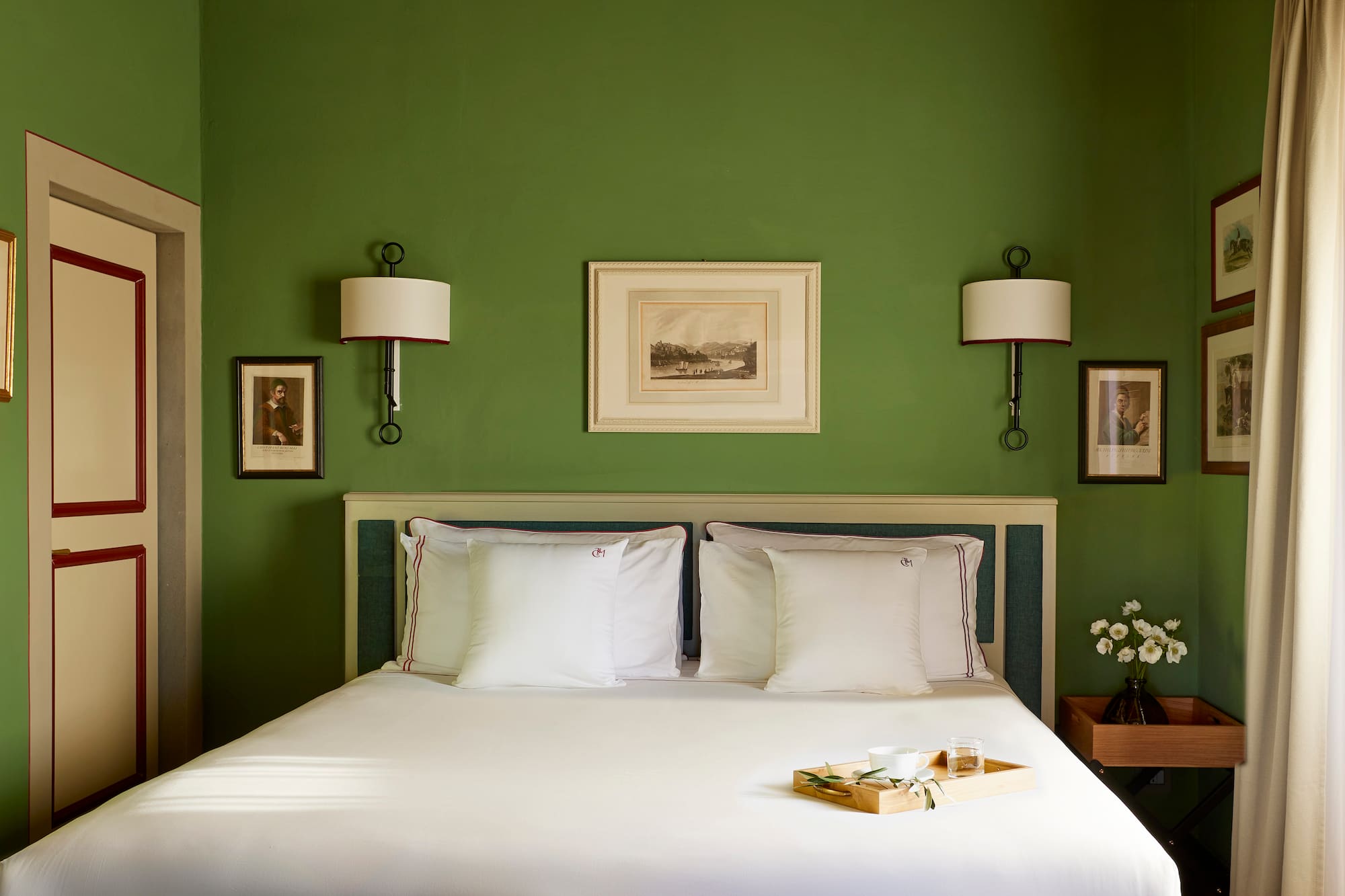 a bed with white sheets and pillows in a green room