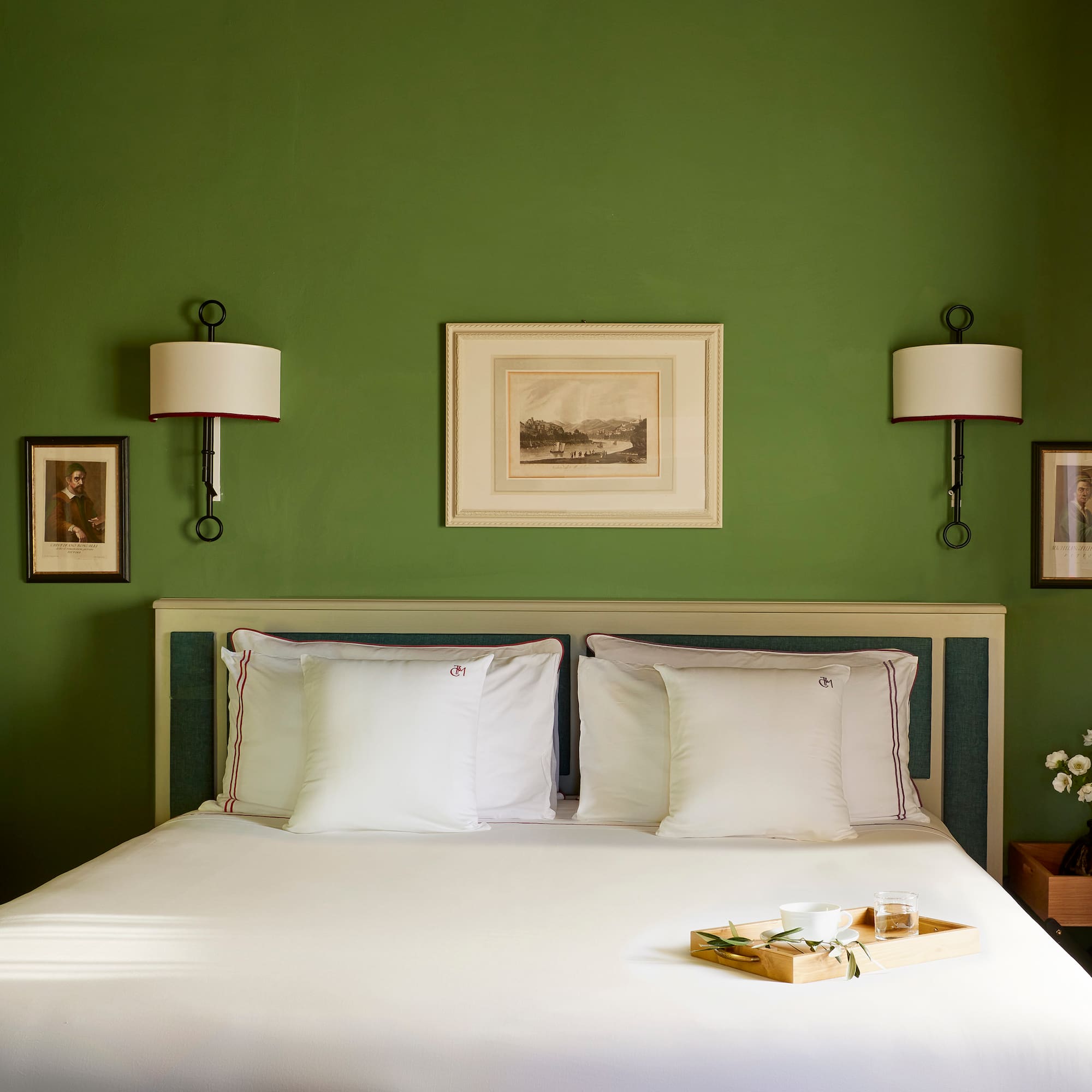 a bed with white sheets and pillows in a green room