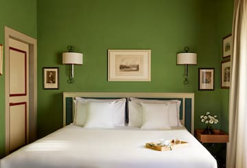 a bed with white sheets and pillows in a green room