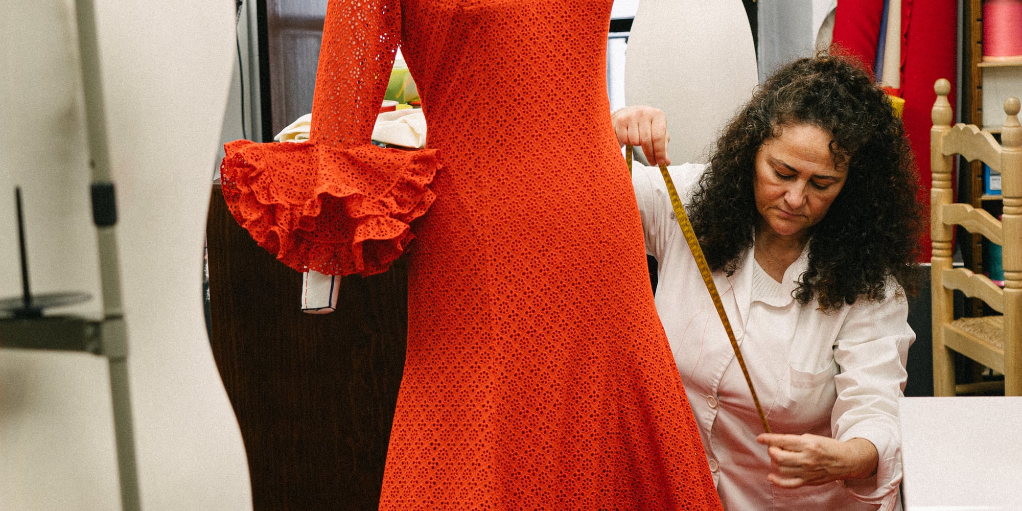 a woman measuring a dress on a mannequin