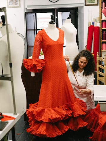 a woman measuring a dress on a mannequin