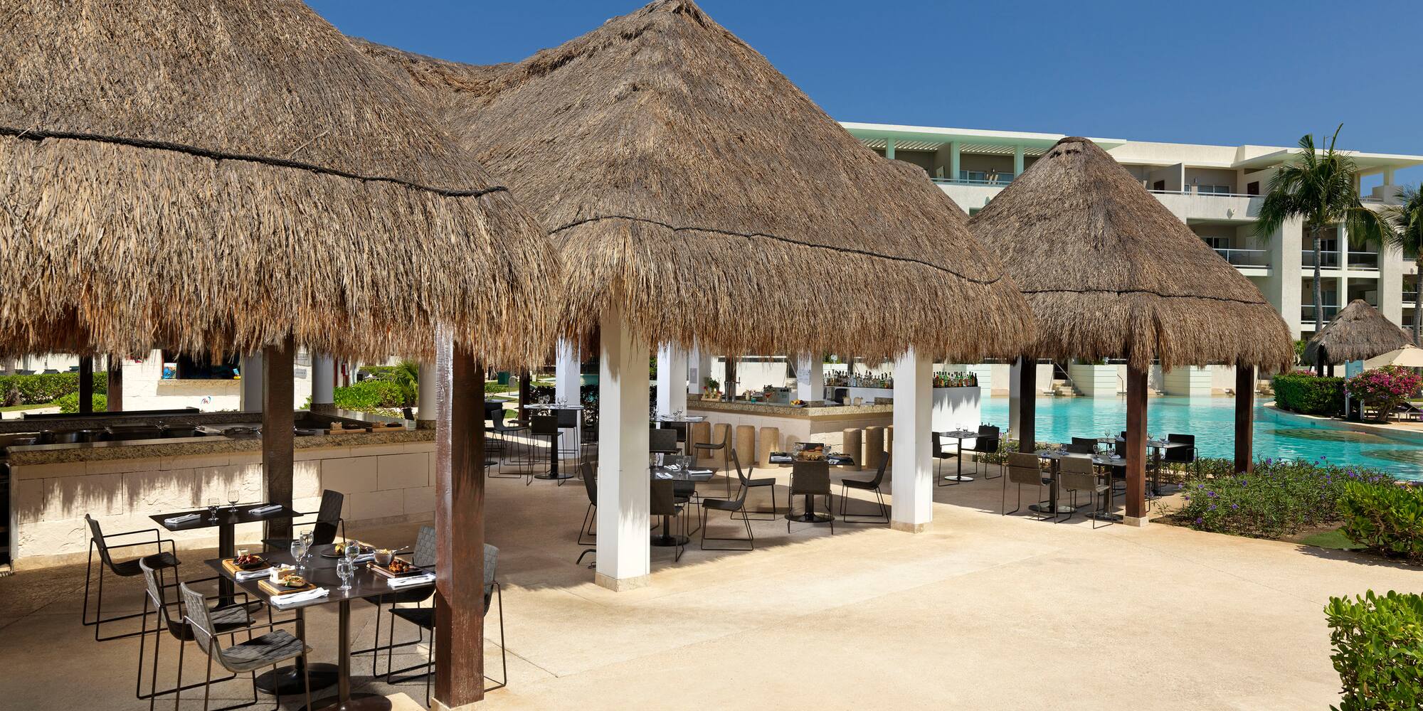 a group of tables and chairs under a pool