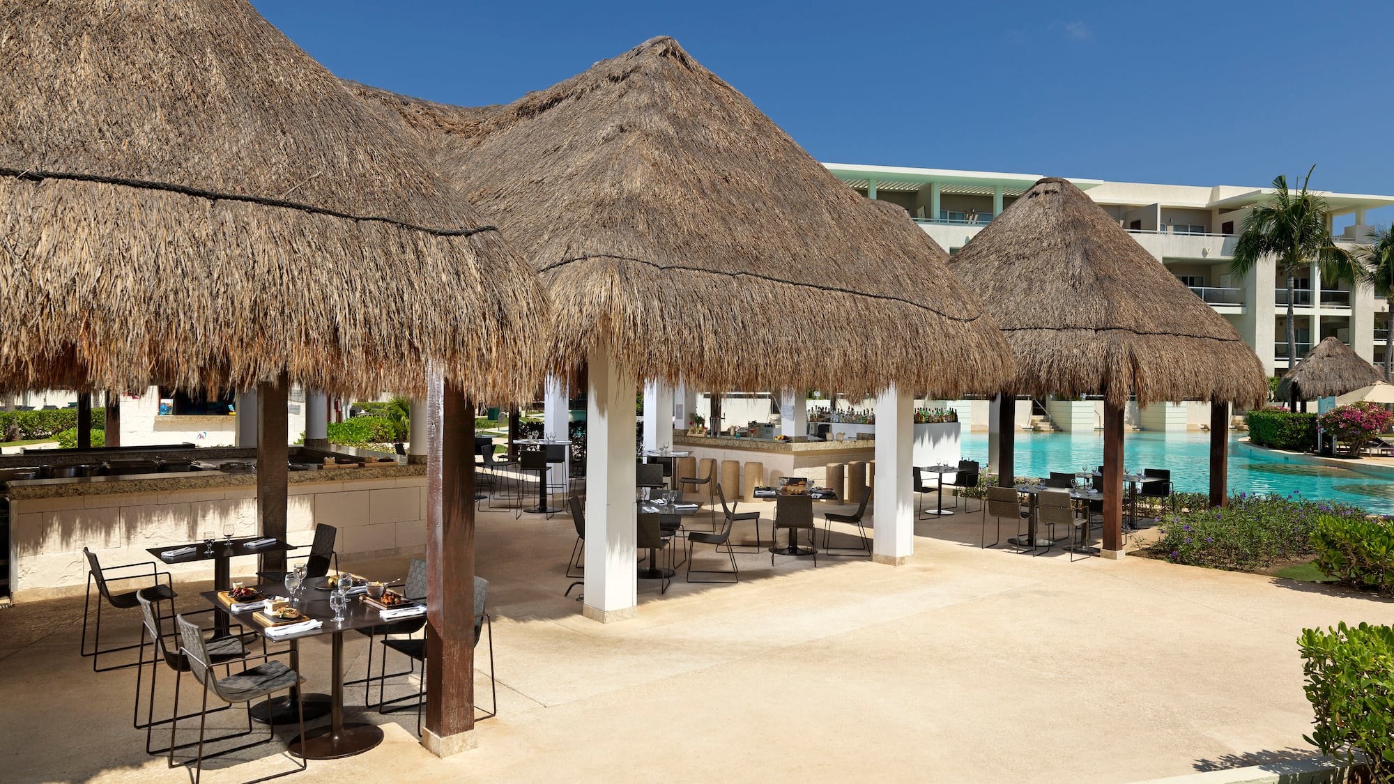 a group of tables and chairs under a pool