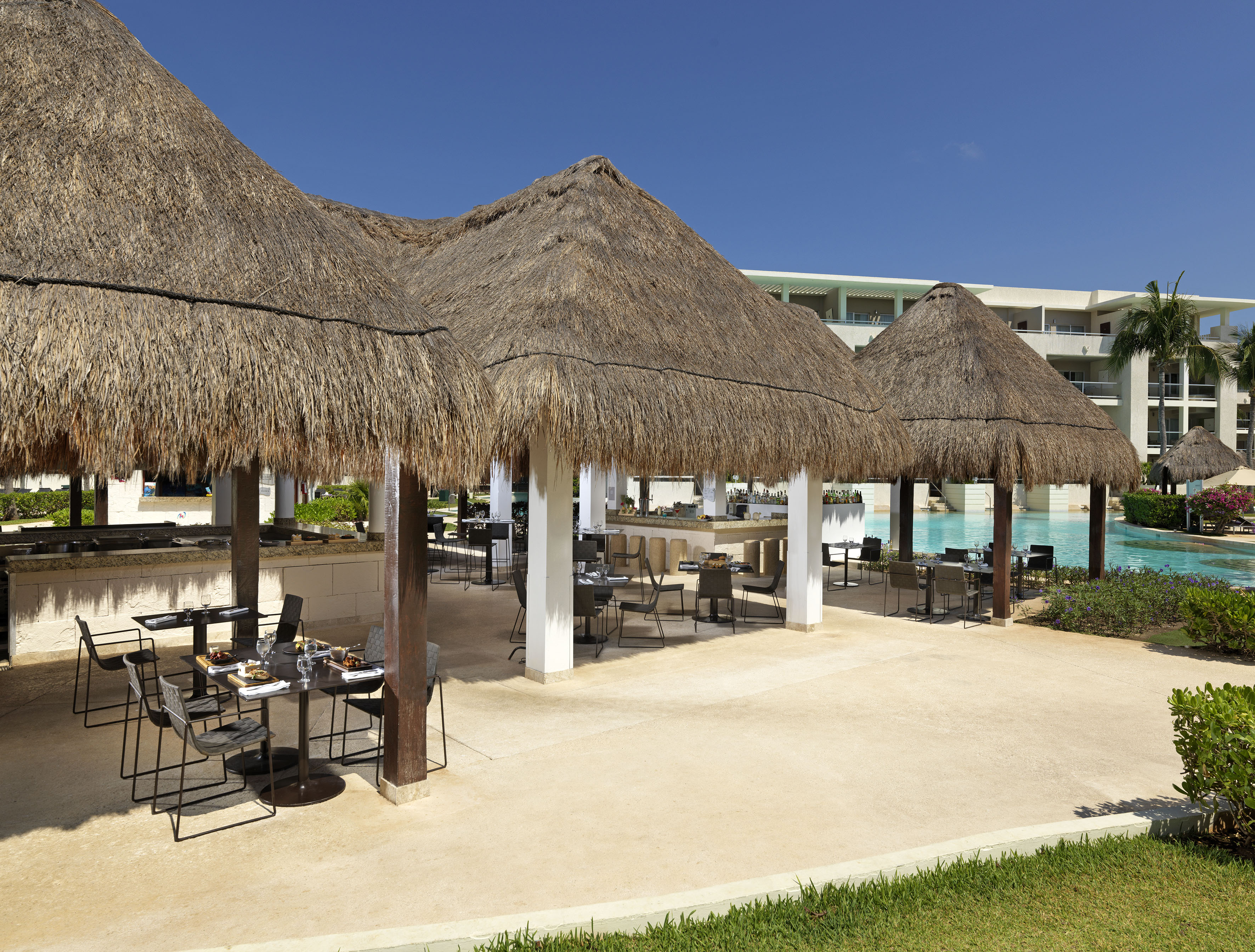 a group of tables and chairs under a pool
