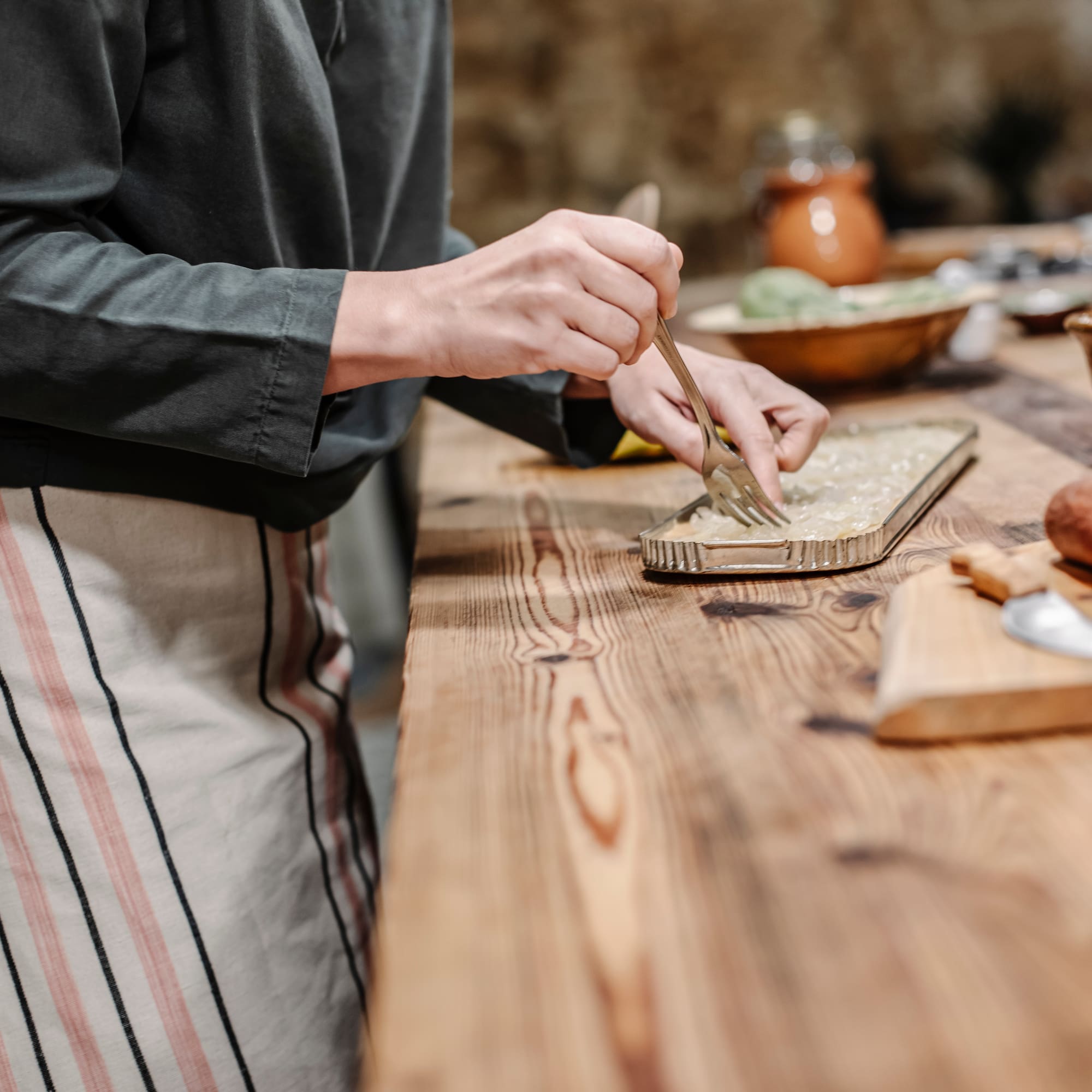 a person holding a fork and a tray of food