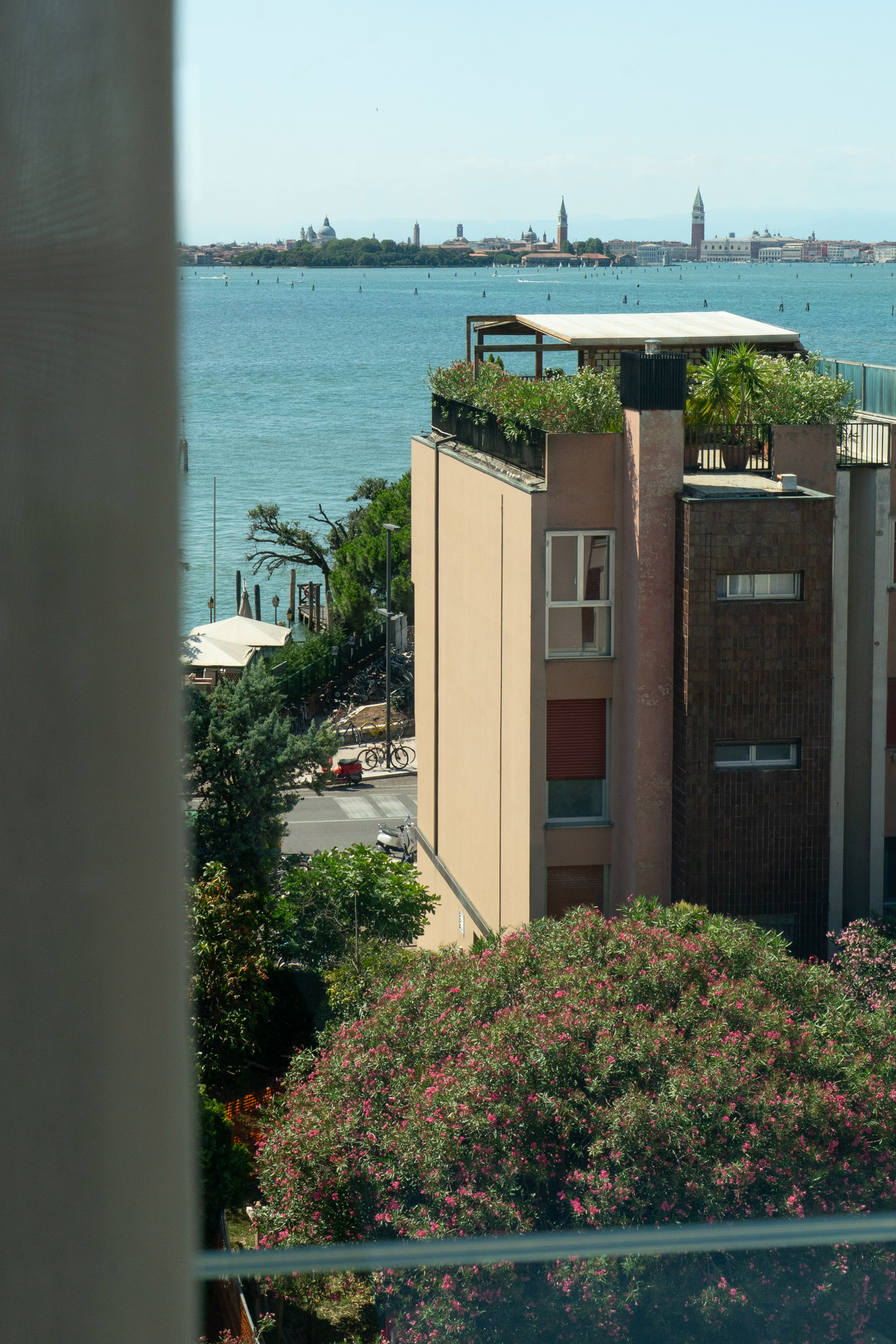 Venice lagoon view: Rooftop garden on modern building, distant historic skyline.