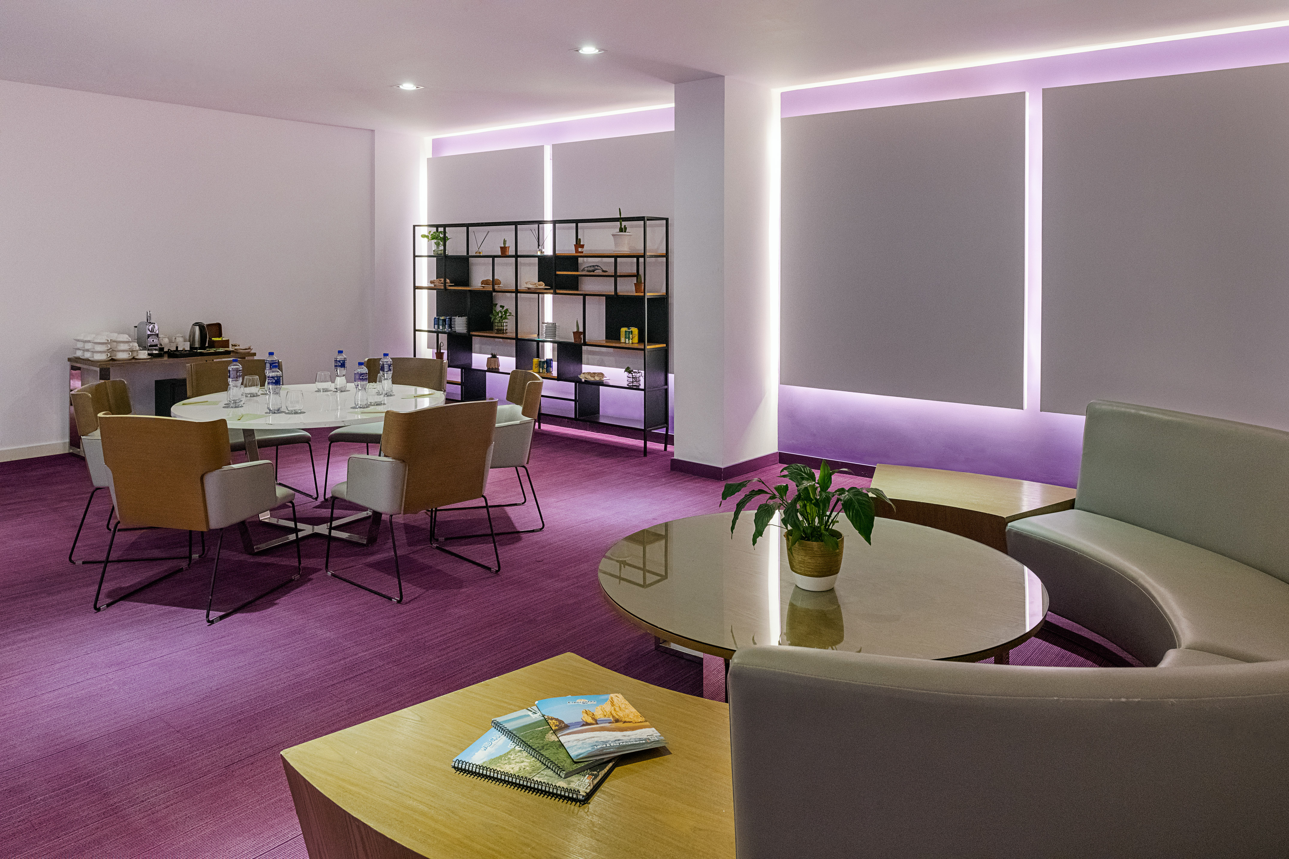 Modern meeting space with purple carpet, round table, and lounge seating.
