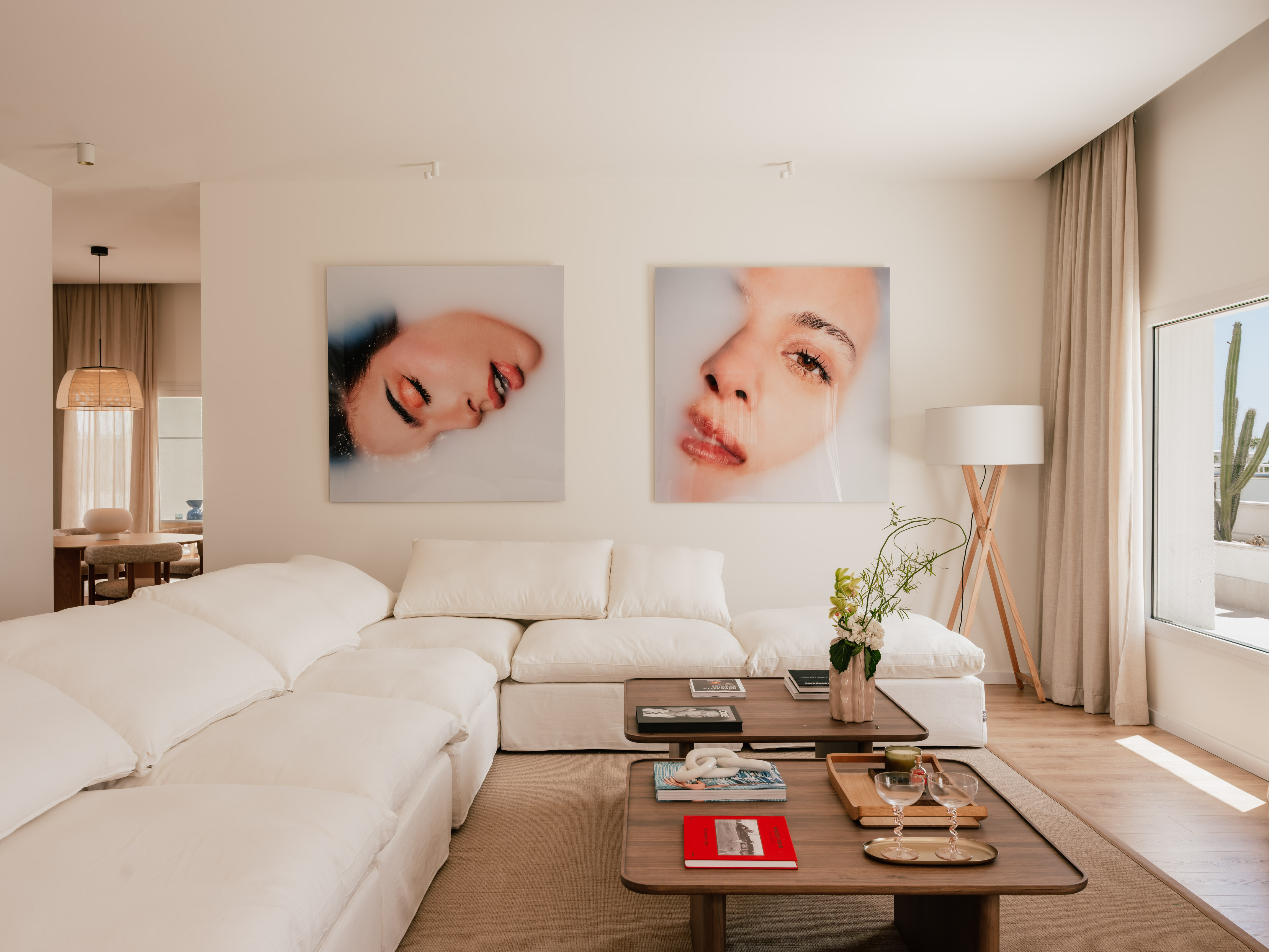 Modern living room with white sectional sofa, coffee tables, and striking wall art.