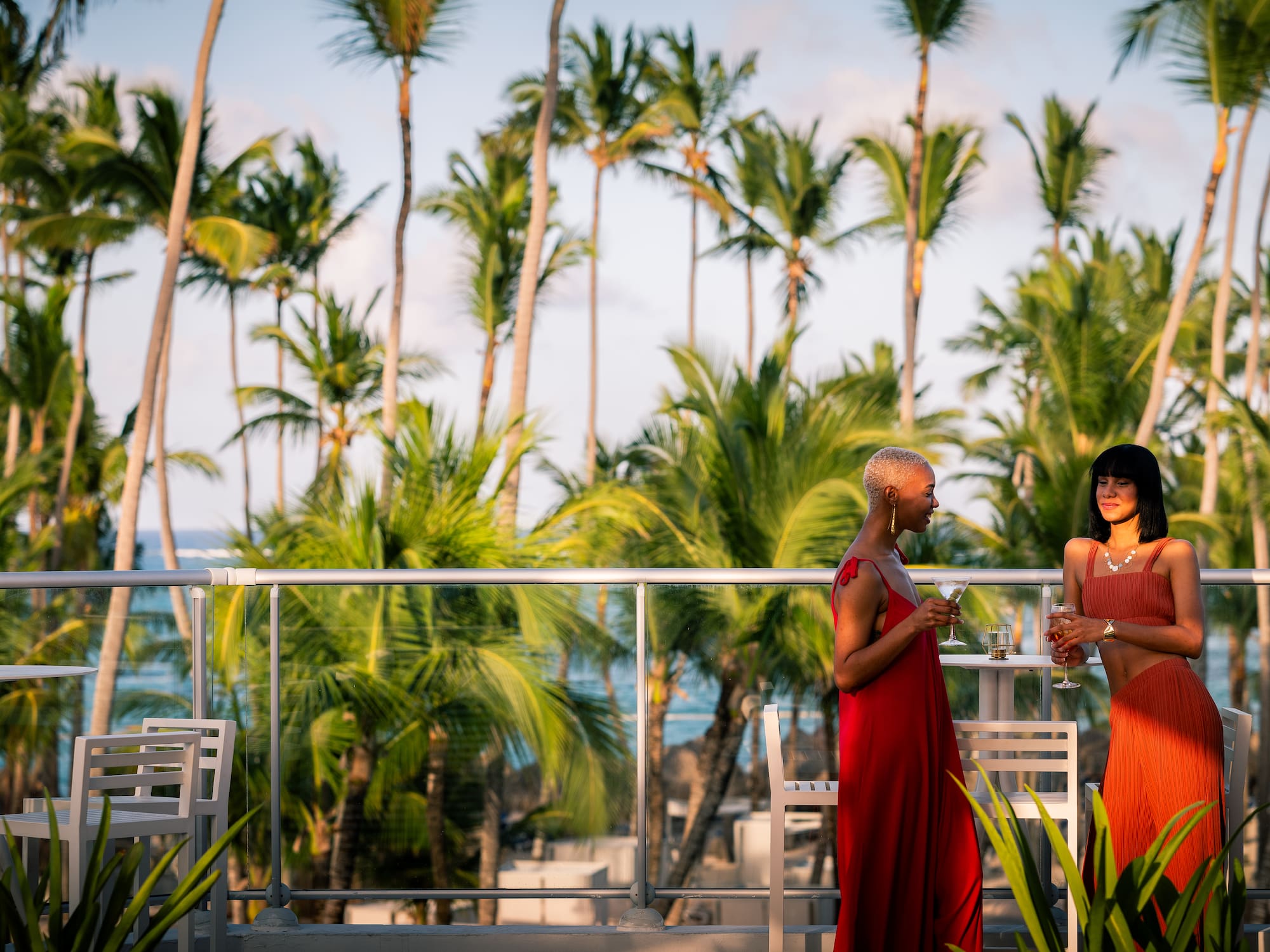 a group of women standing on a balcony with palm trees