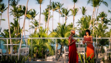 a group of women standing on a balcony with palm trees