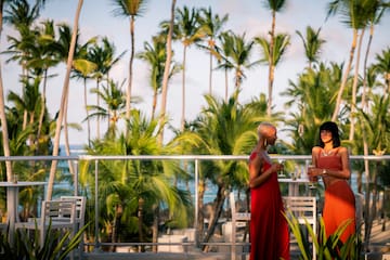 a group of women standing on a balcony with palm trees