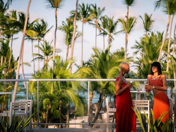 a group of women standing on a balcony with palm trees