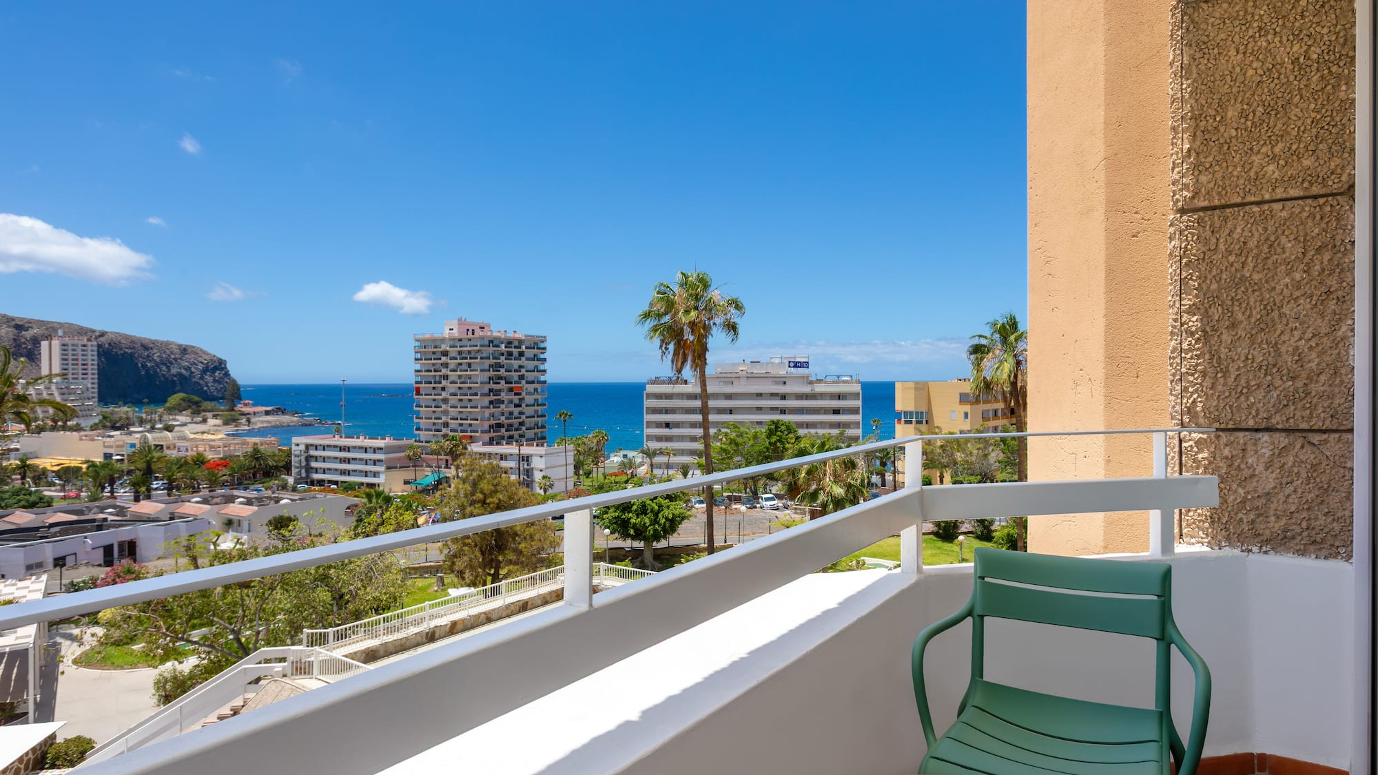 a balcony with a chair and table overlooking a body of water