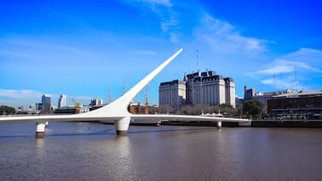 a bridge over water with a large building in the background
