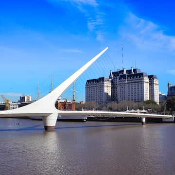 a bridge over water with a large building in the background