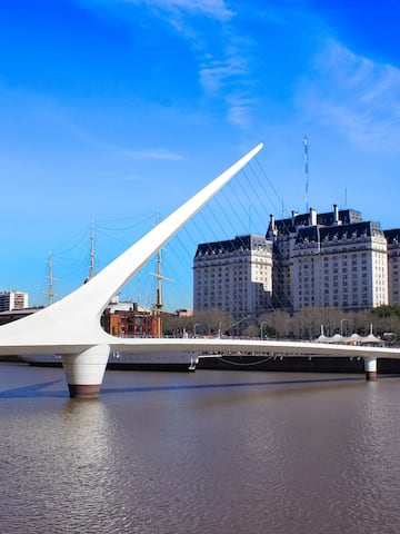 a bridge over water with a large building in the background