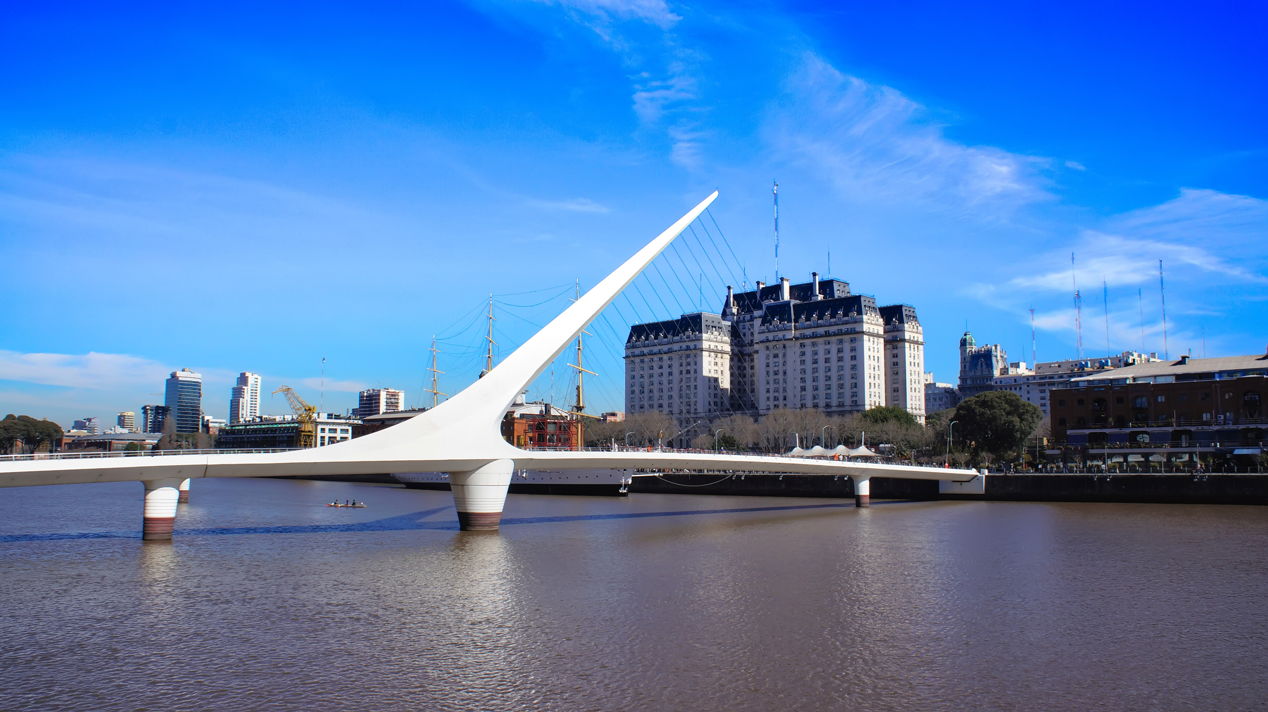 Puente de la Mujer bridge over water, Buenos Aires skyline, historic buildings.