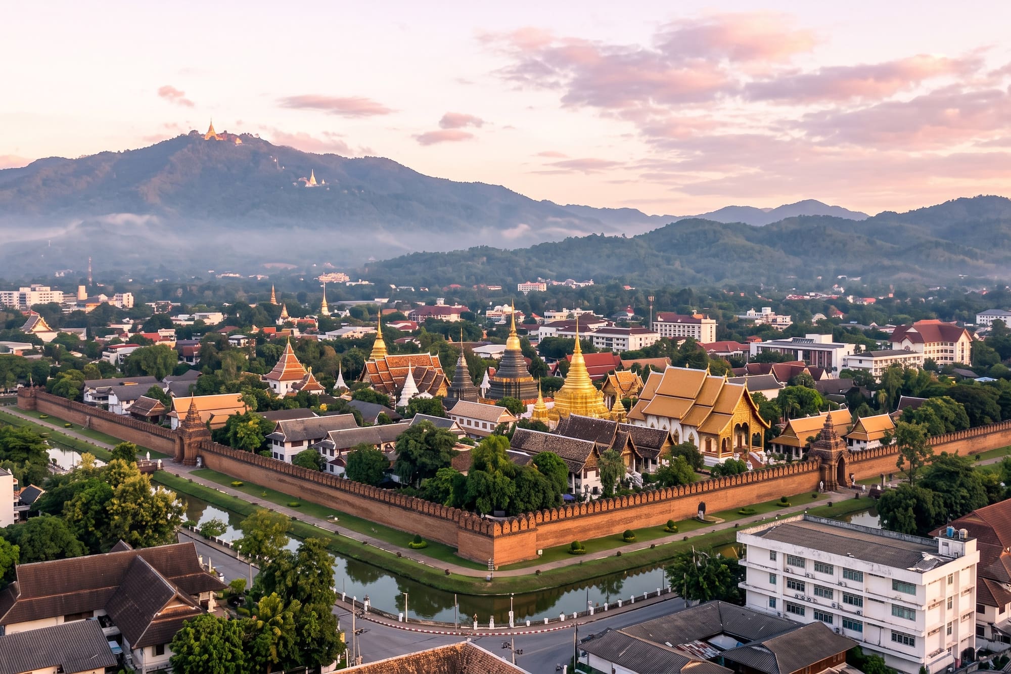 Chiang Mai Old City: temples, moat, wall, and mountains at sunrise.