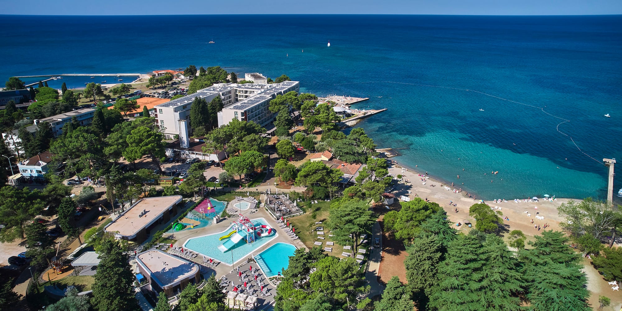 a beach with trees and buildings and a body of water