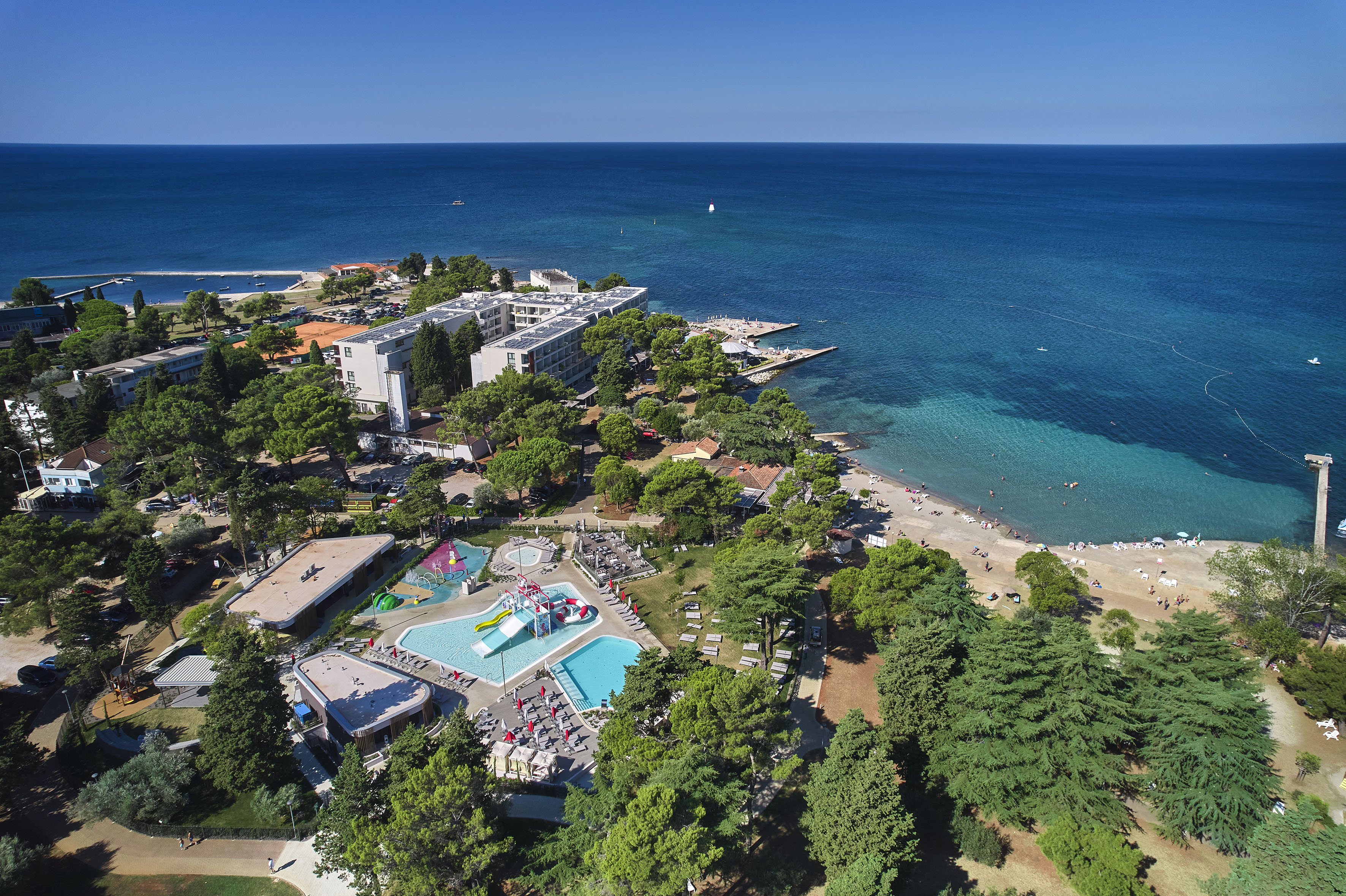 a beach with trees and buildings and a body of water