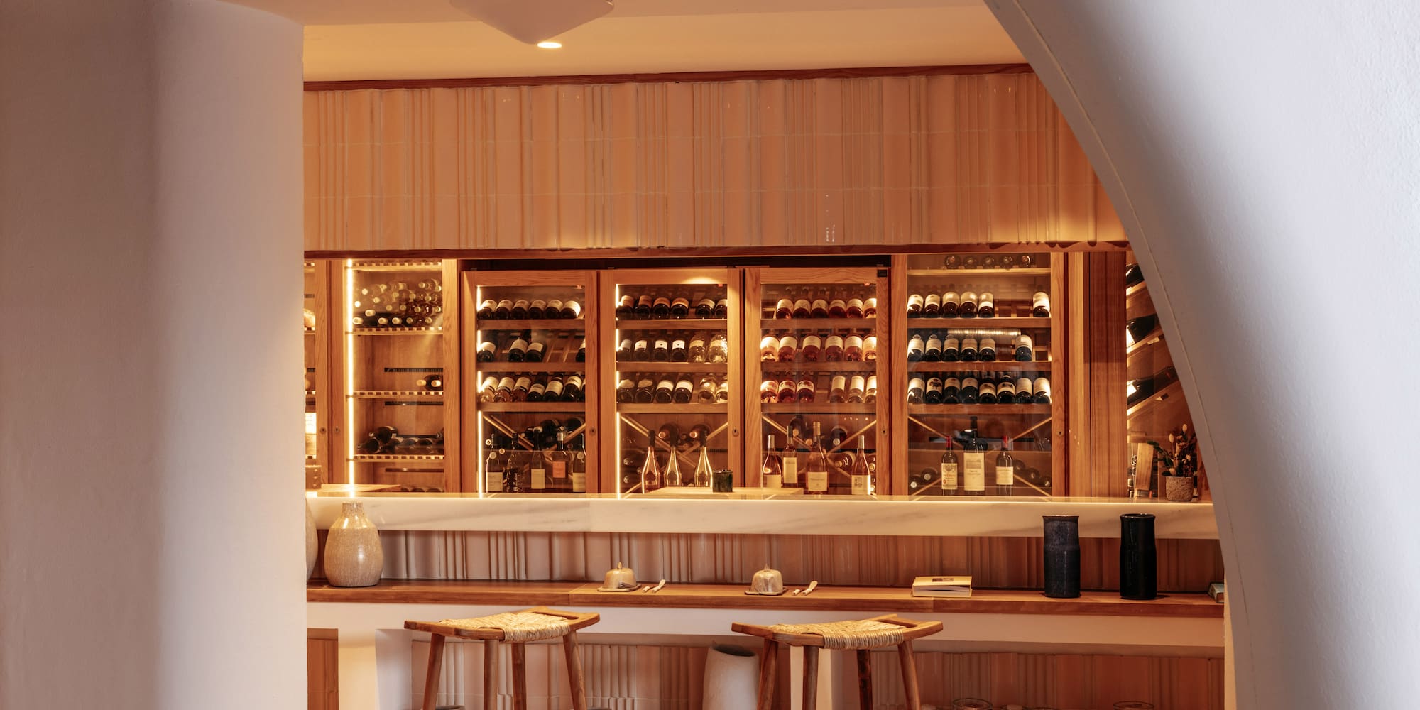 a bar with shelves of wine and stools